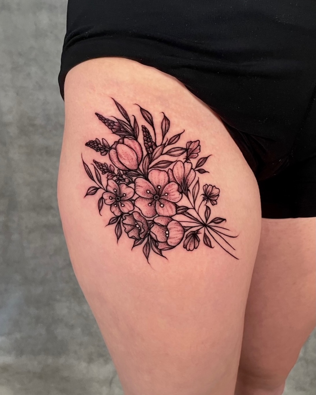 Floral bouquet black and grey tattoo on the thigh by Austin Clark