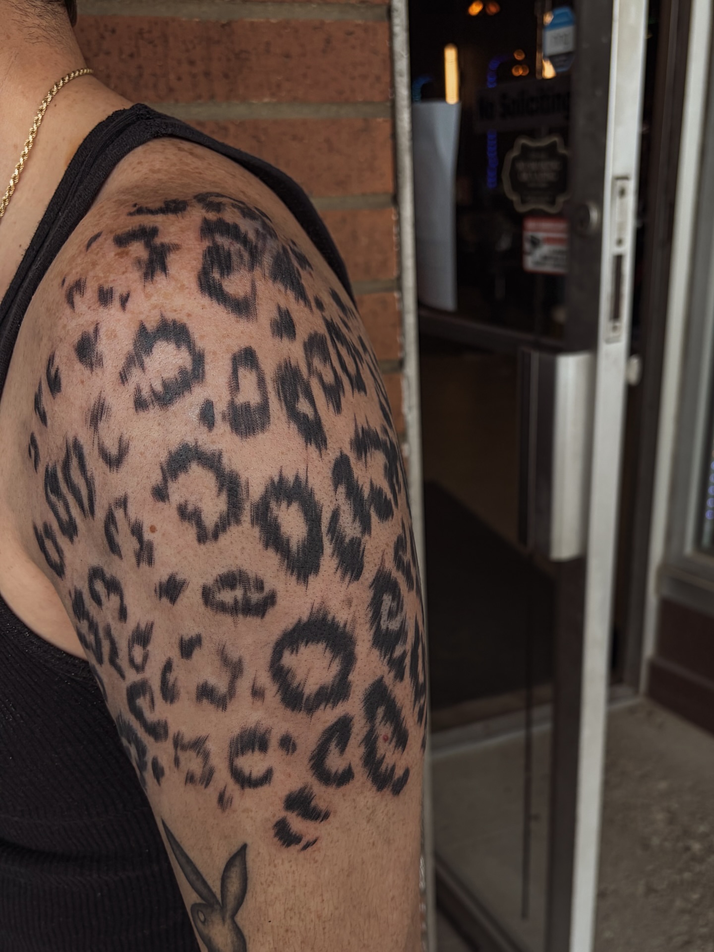 Leopard print black and grey tattoo on the upper arm by ⚜️Embodied Tattoo⚜️, Columbus, Ohio