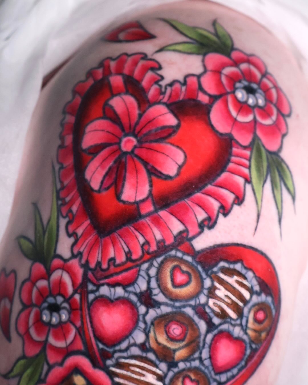 Heart and flowers American traditional tattoo on the upper arm by Bailey Drey