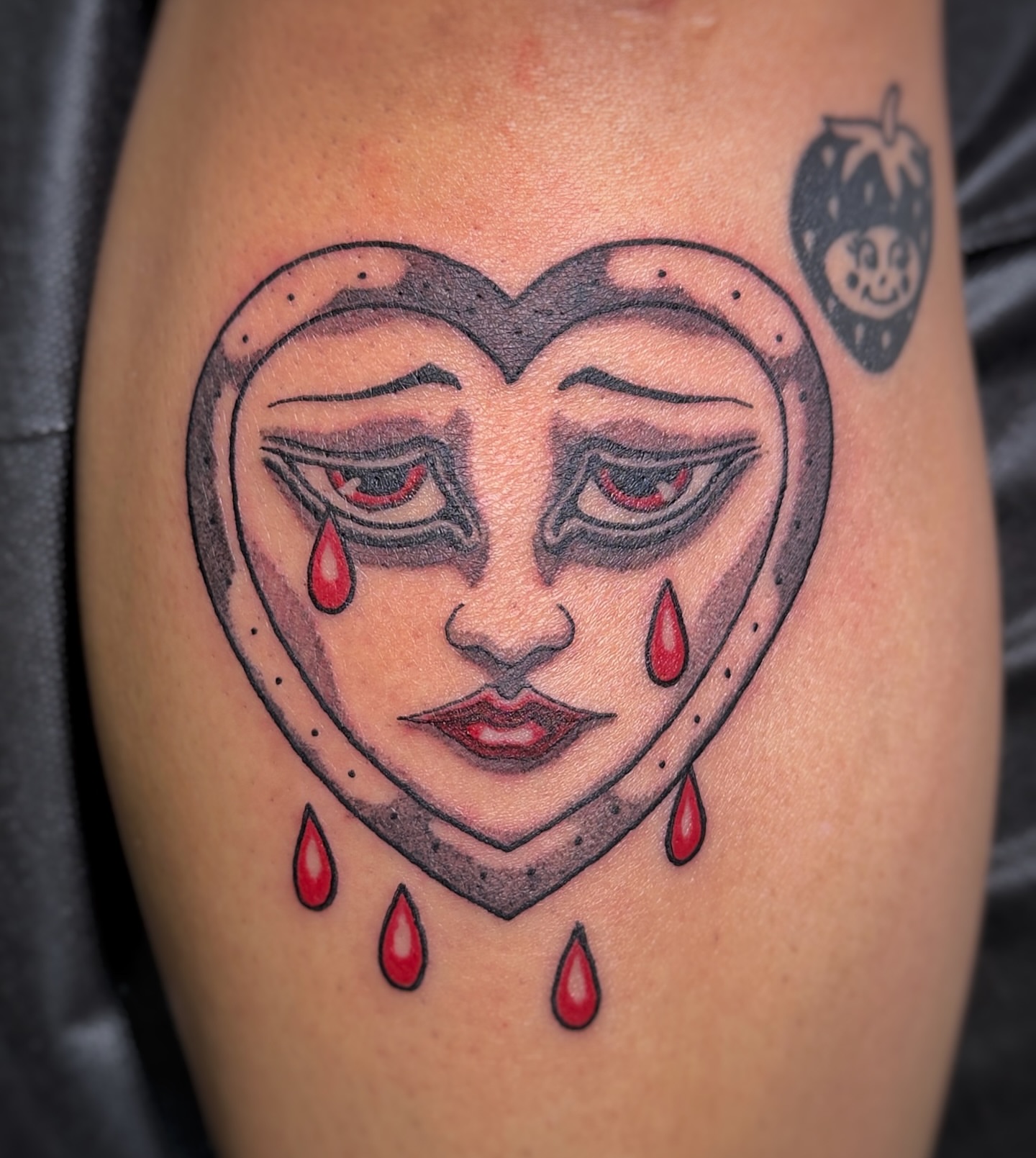 Heart with crying face dark realism tattoo on the thigh by James Bird, Vancouver, British Columbia