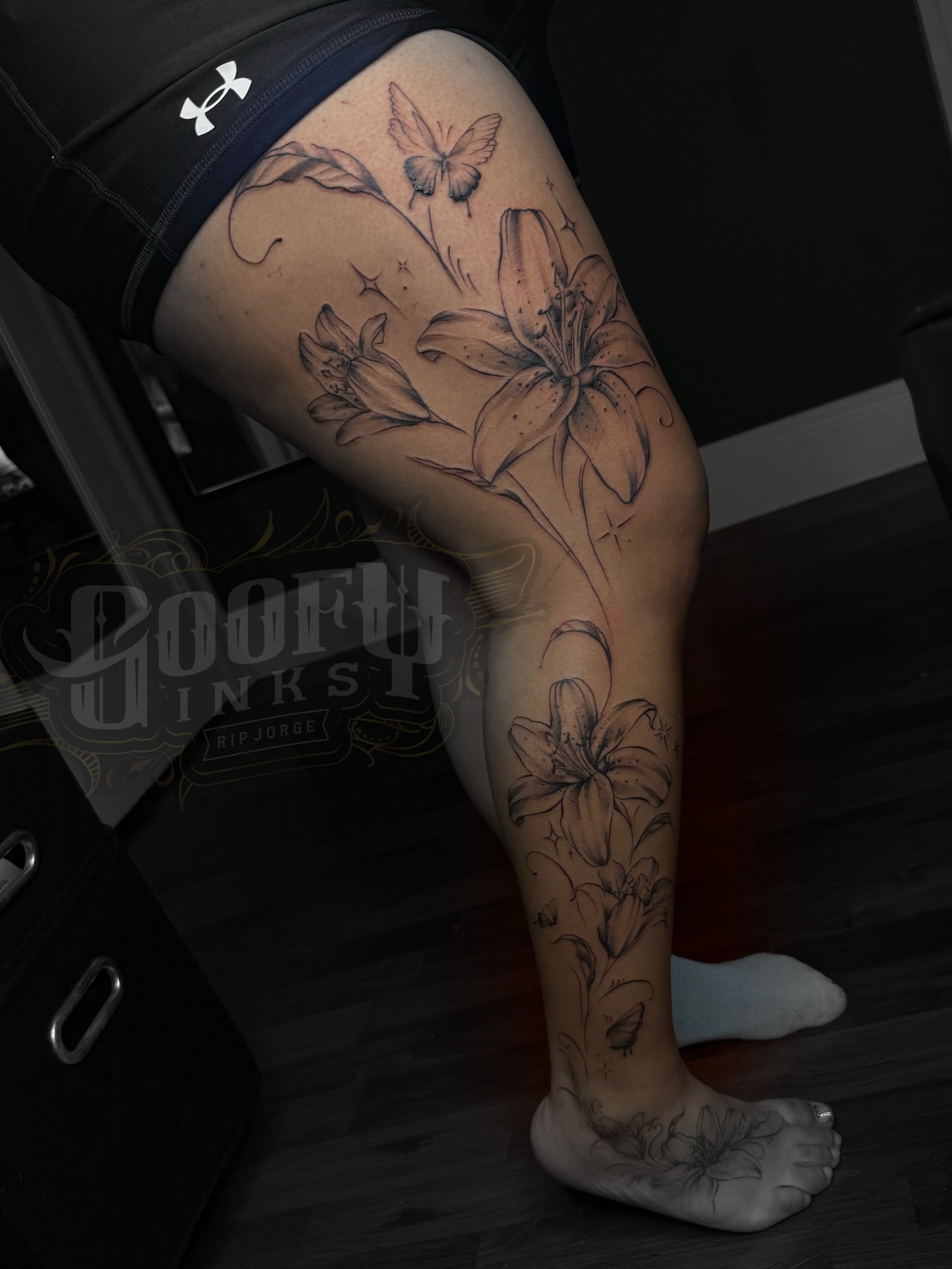 Lilies and butterflies black and grey tattoo on the thigh by Gooofy’s Ink 💸✍🏽 18+