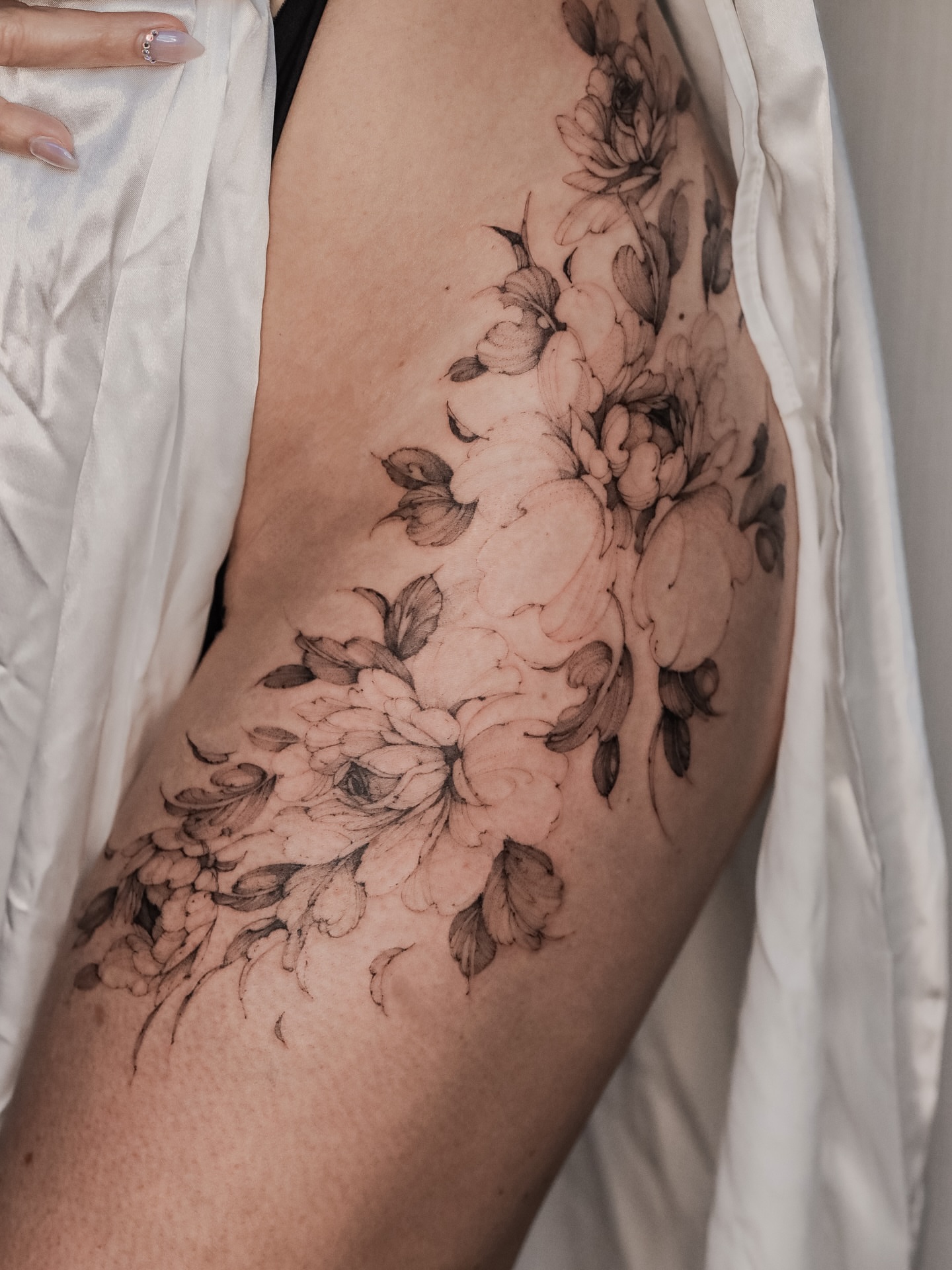 Floral bouquet black and grey tattoo on the thigh by Maria