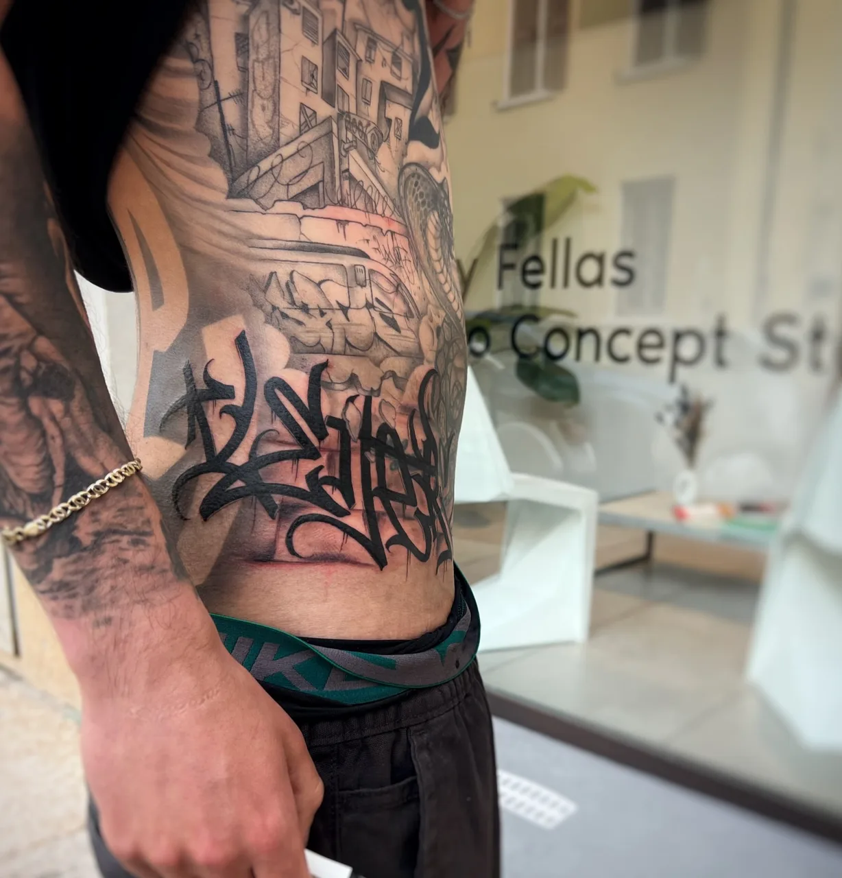 Graffiti-style lettering black and grey tattoo on the torso by Blot_Tattoo