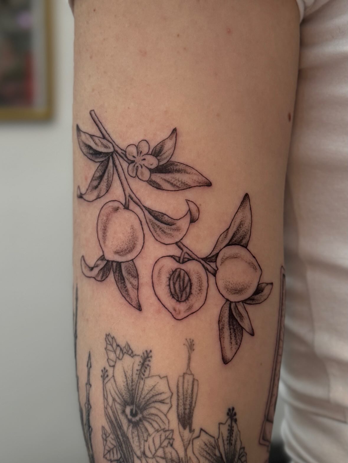 Peach branch black and grey tattoo on the forearm by Kamakana Pankiwska