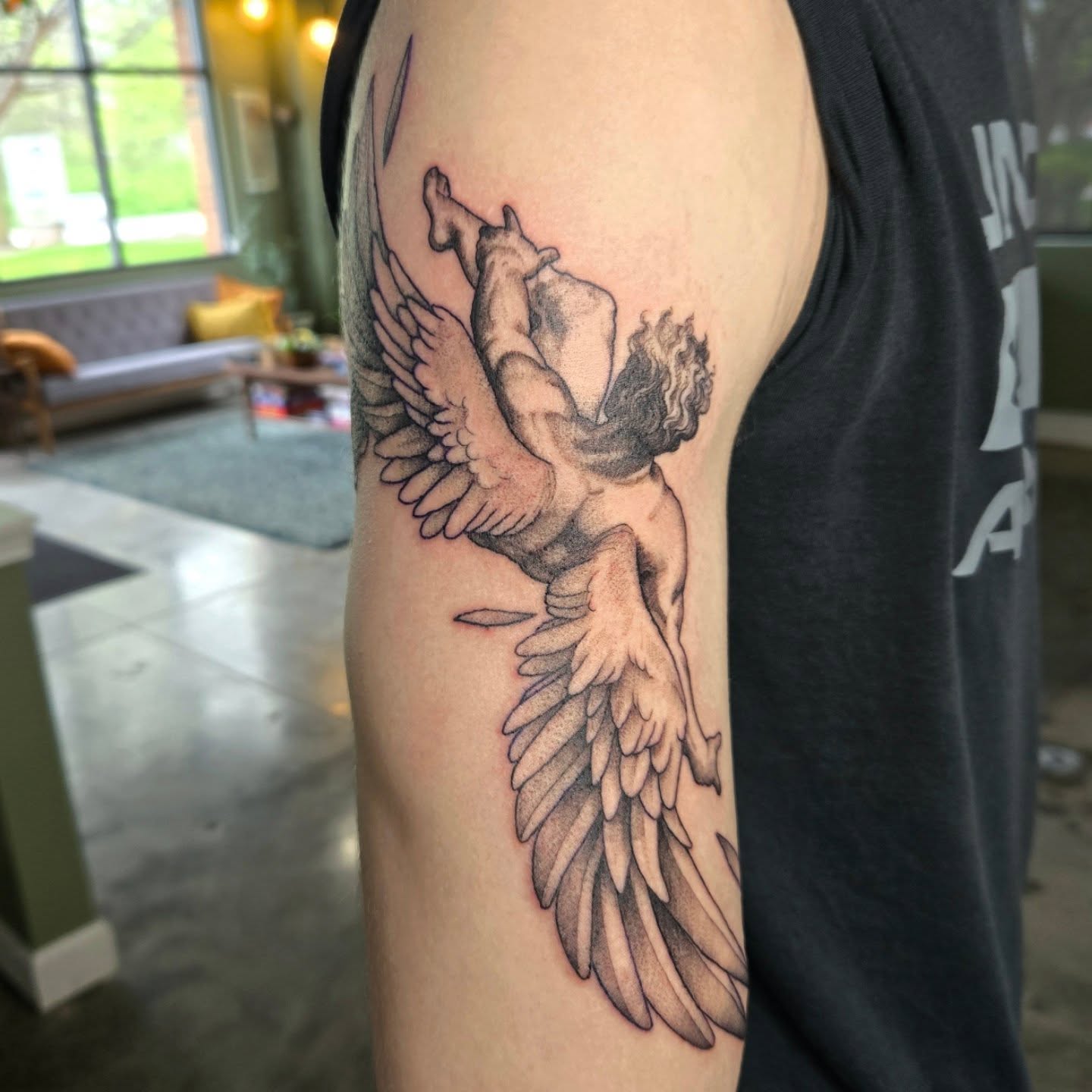 Winged cherub black and grey tattoo on the upper arm by Amanda Hinrichs