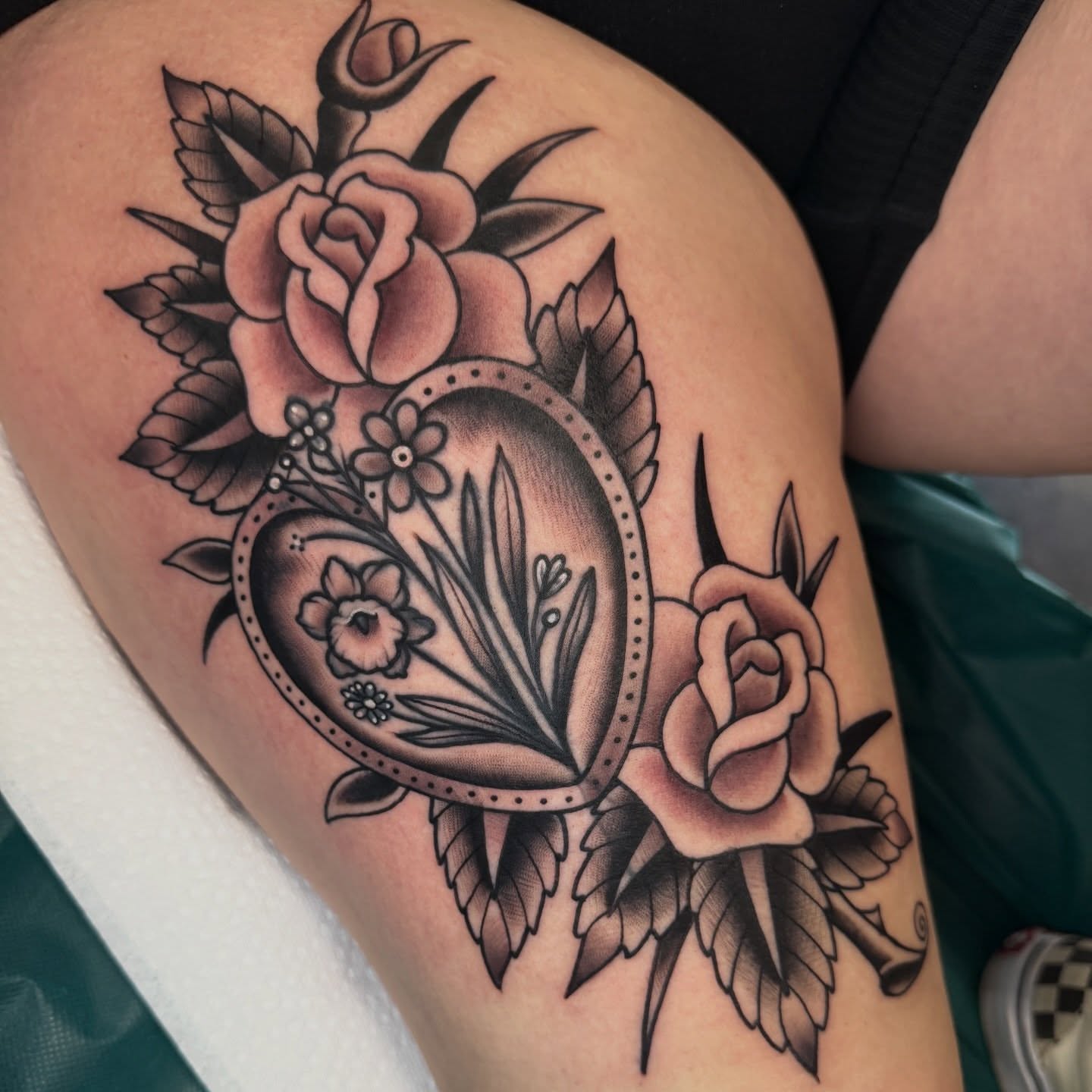 Heart with roses American traditional tattoo on the thigh by Christopher Mikesell