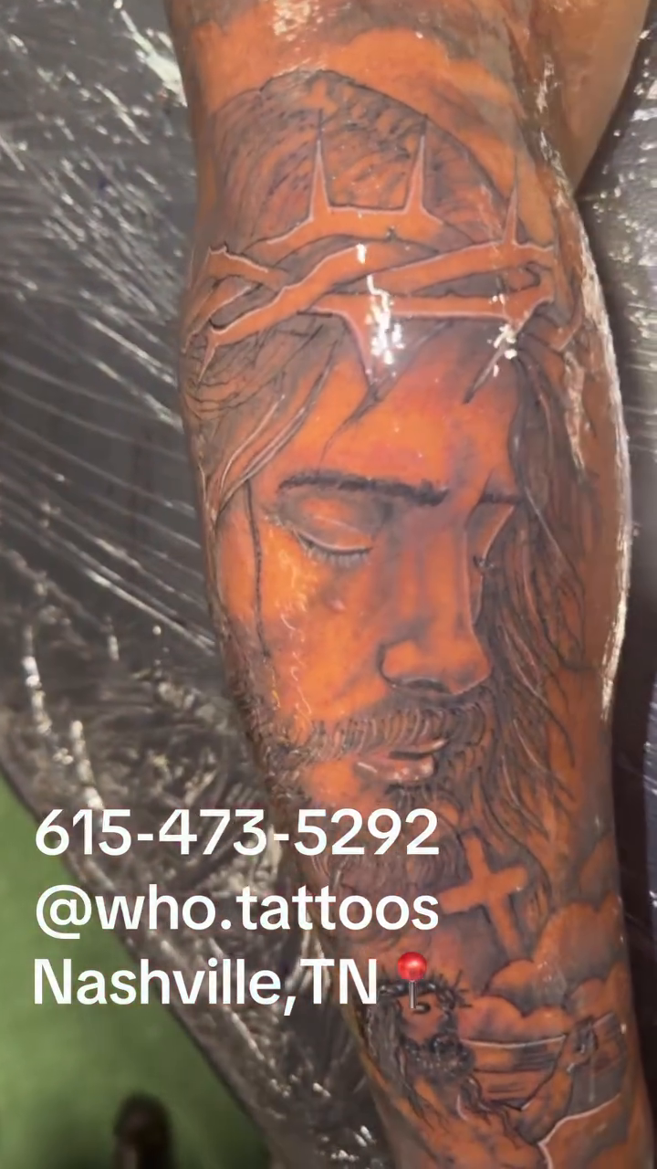 Jesus Christ portrait with surrounding imagery tattoo on the upper arm by Marcus Carter