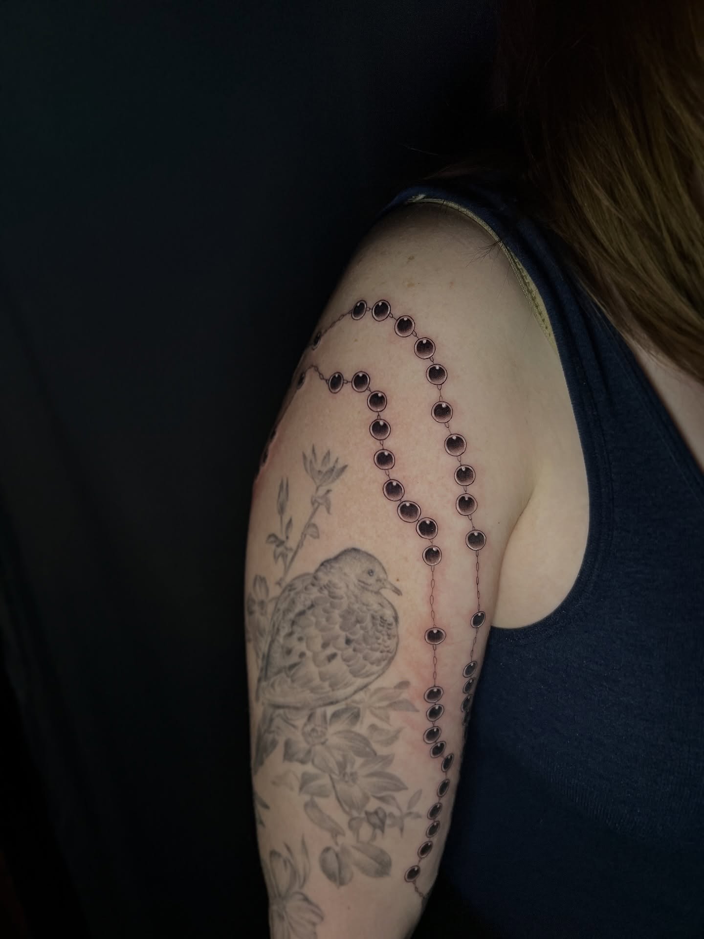 Rosary and dove dotwork tattoo on the shoulder by Jen Rahman