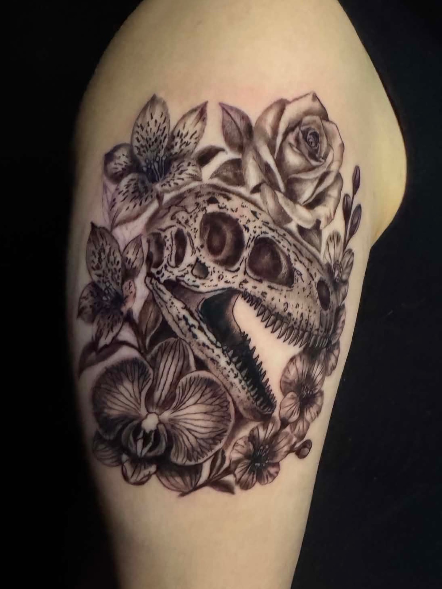 Skull and flowers realism tattoo on the upper arm by Brandiane Wells