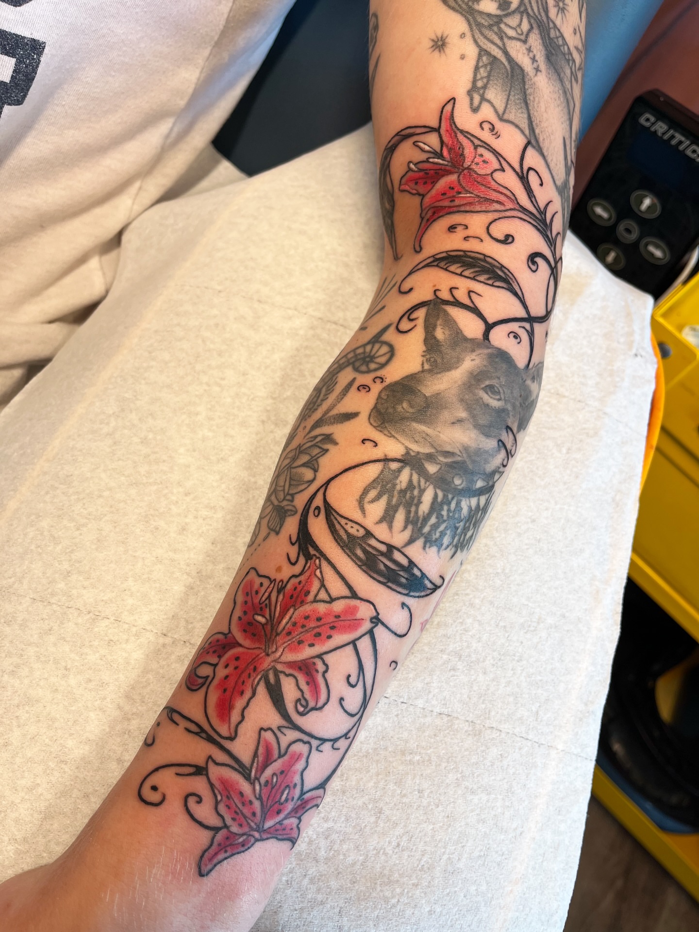 Dog and lilies American traditional tattoo on the forearm by Allyson Blessing Tattoos