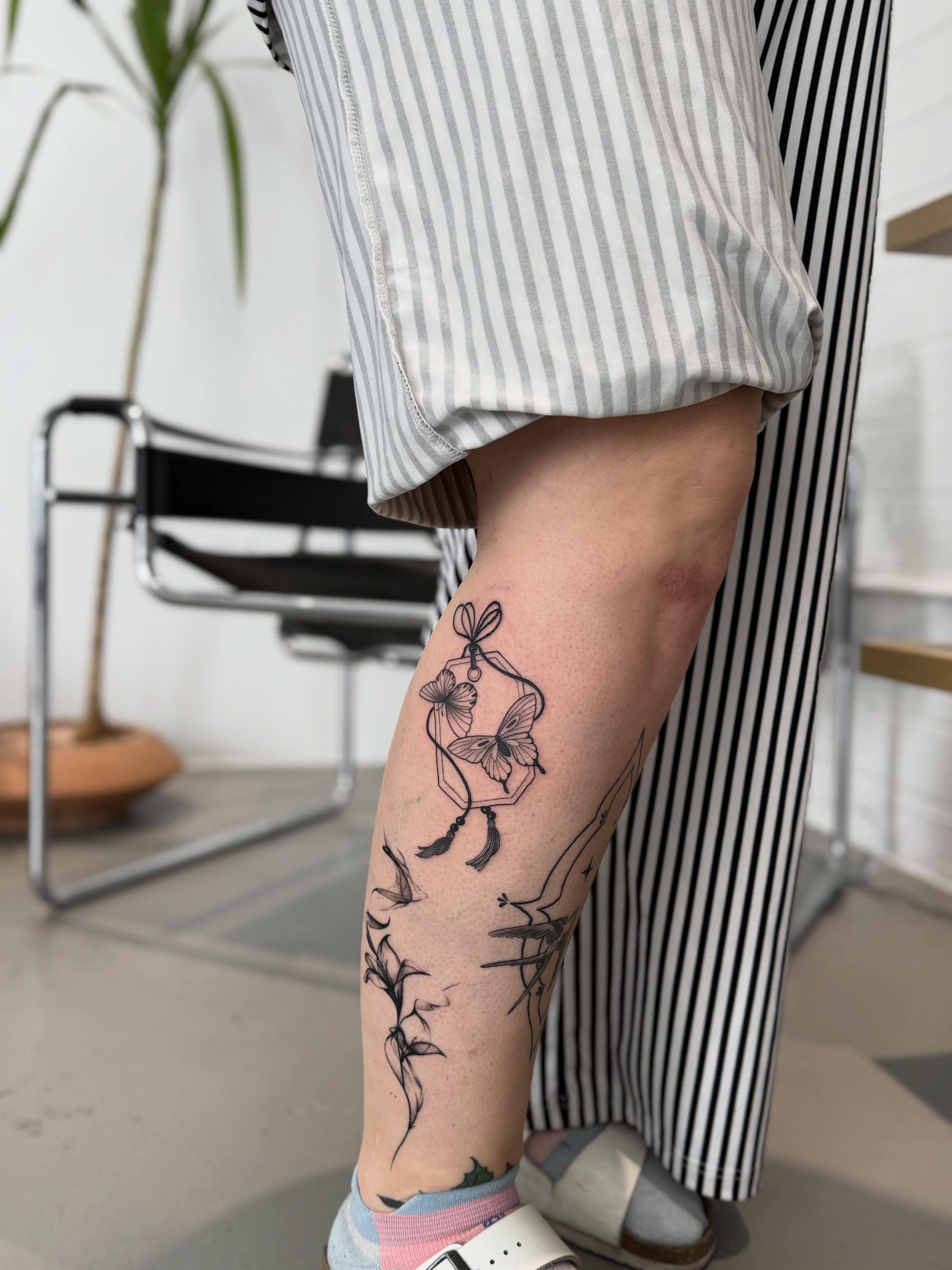 Butterfly and floral black and grey tattoo on the calf by Julianna