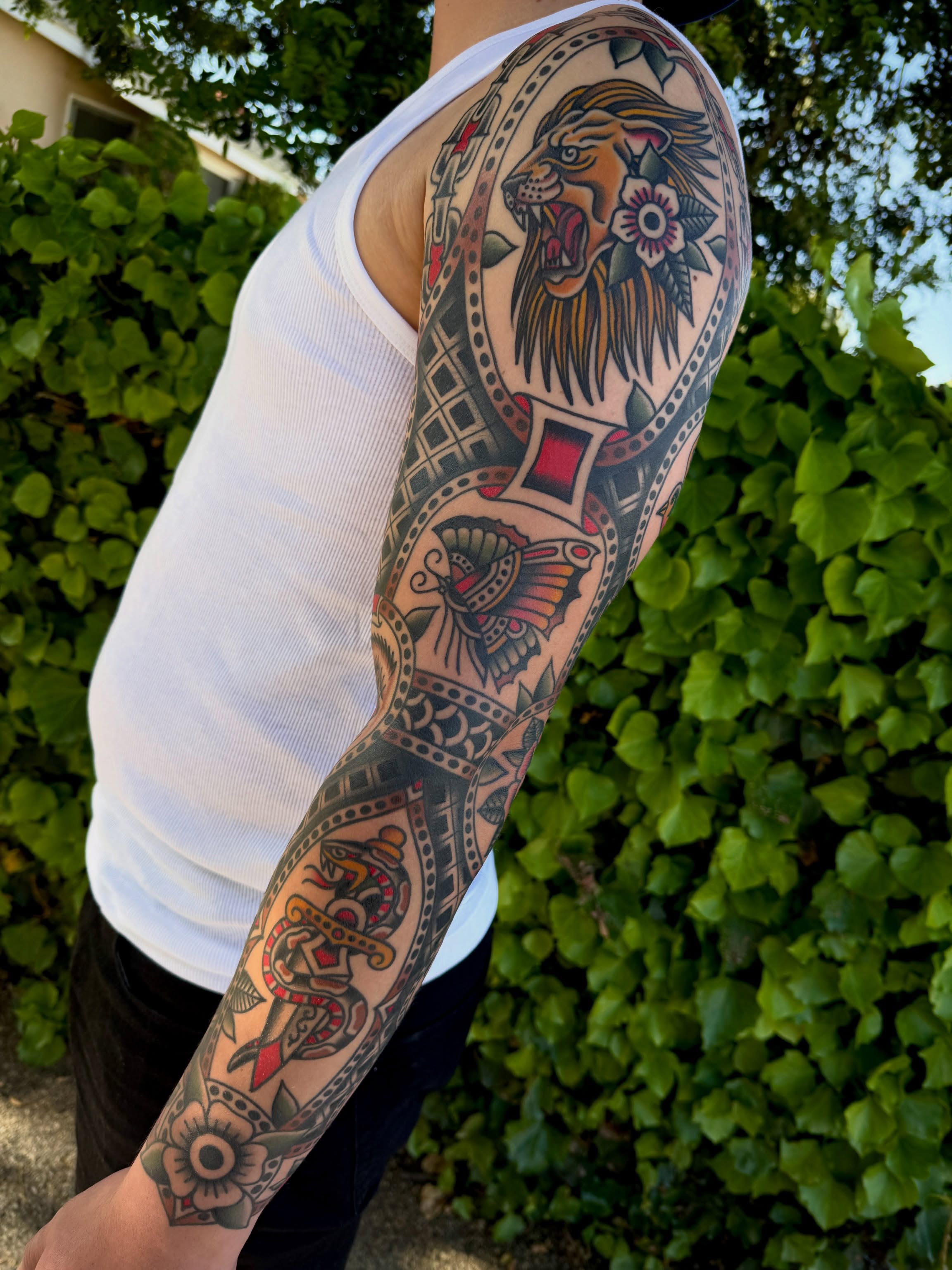 Lion and floral patterns American traditional tattoo on the forearm by Jordan Allen