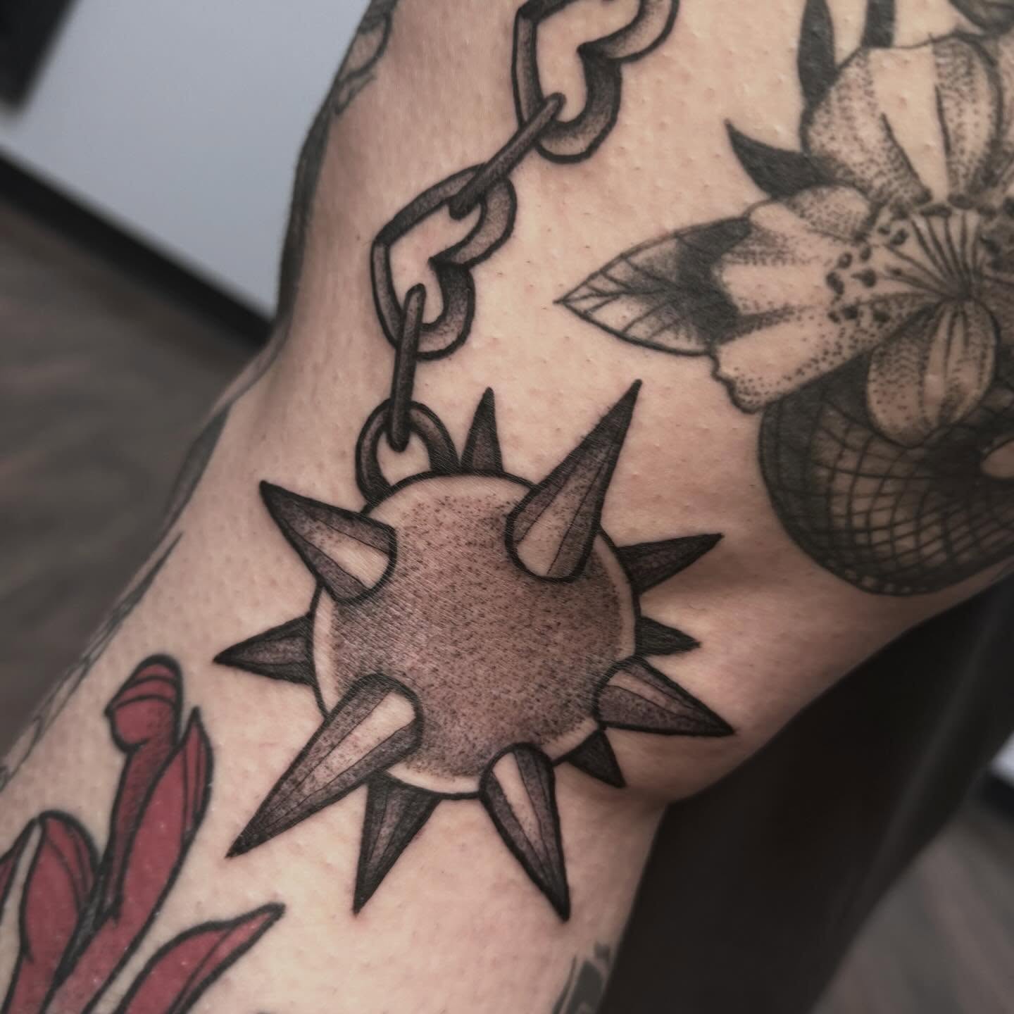 Spiked ball and chain black and grey tattoo on the forearm by Sarah Foltz