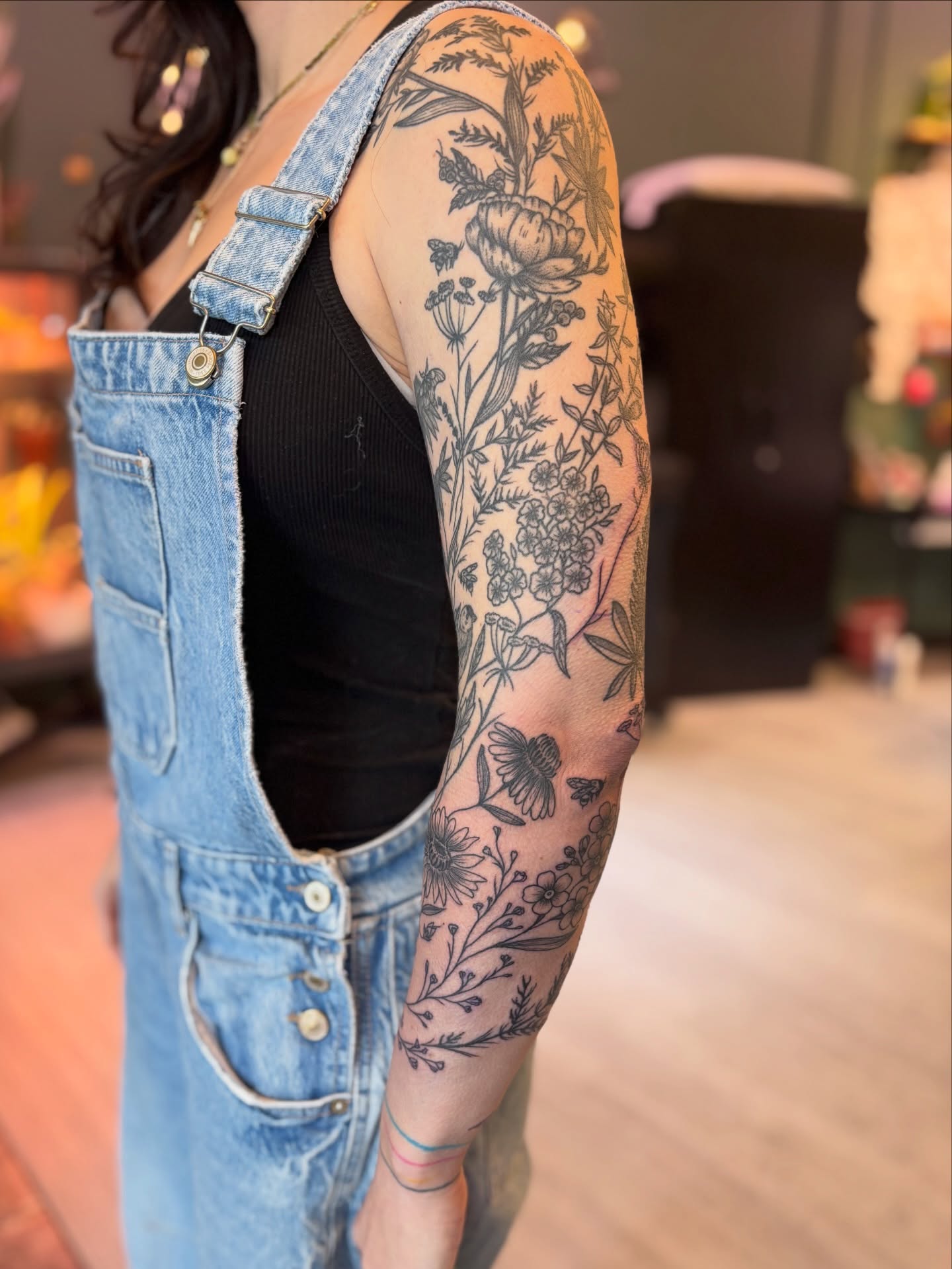 Floral arrangement black and grey tattoo on the upper arm by Meg Ingersoll