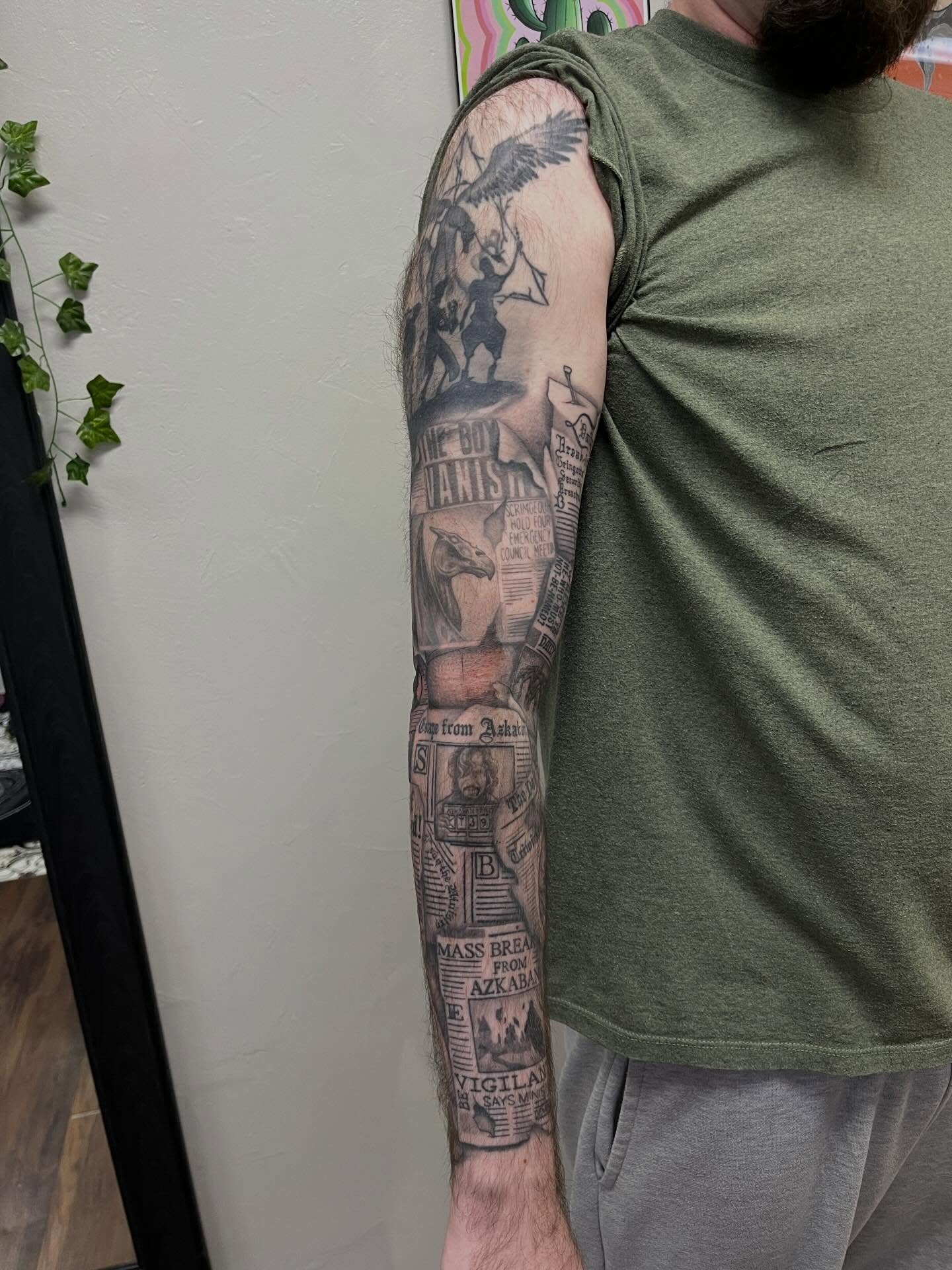 Newspaper headlines black and grey tattoo on the upper arm by Lauren Bumgardner