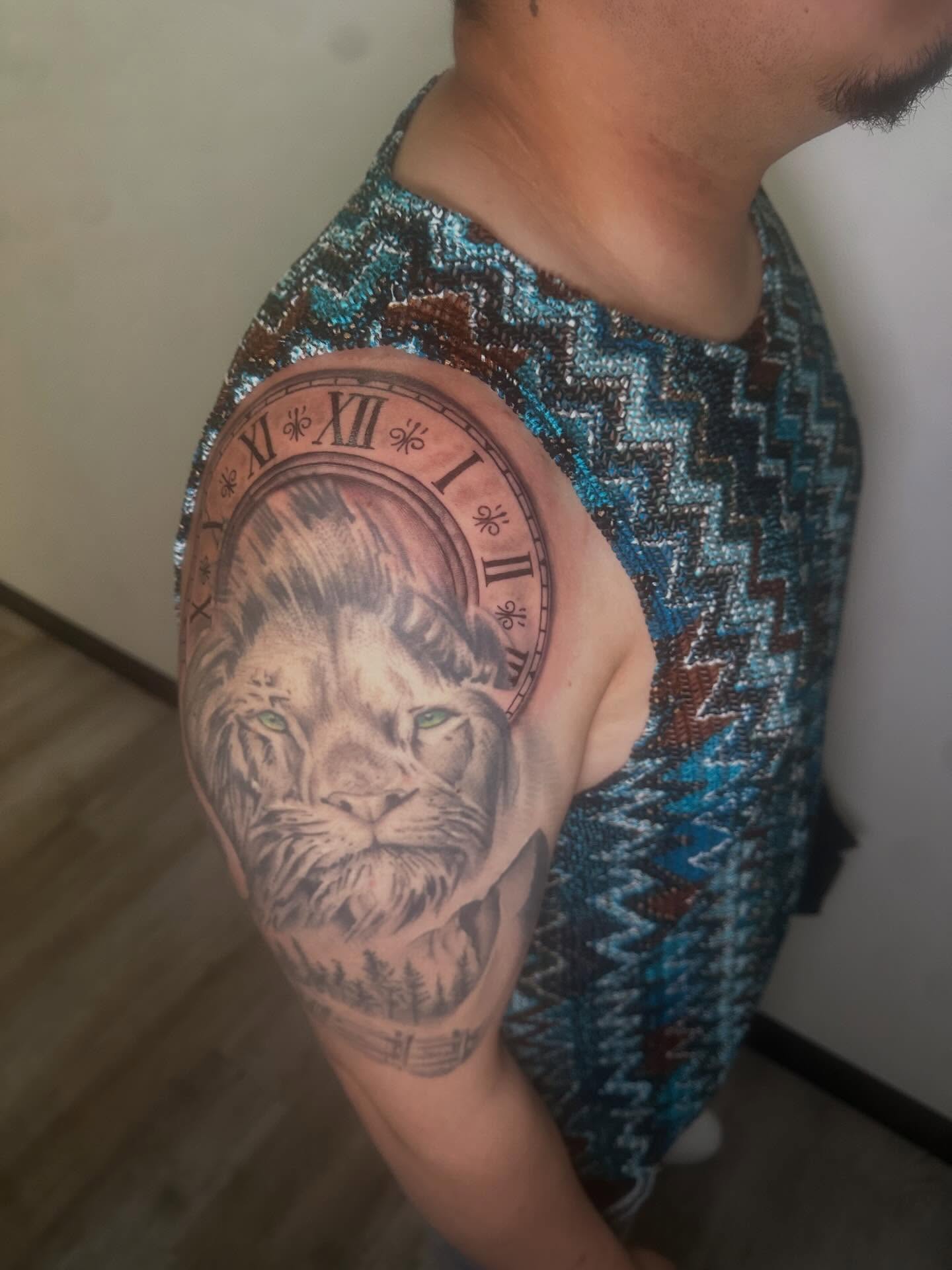 Lion clock realism tattoo on the upper arm by Javierr Jimenezz