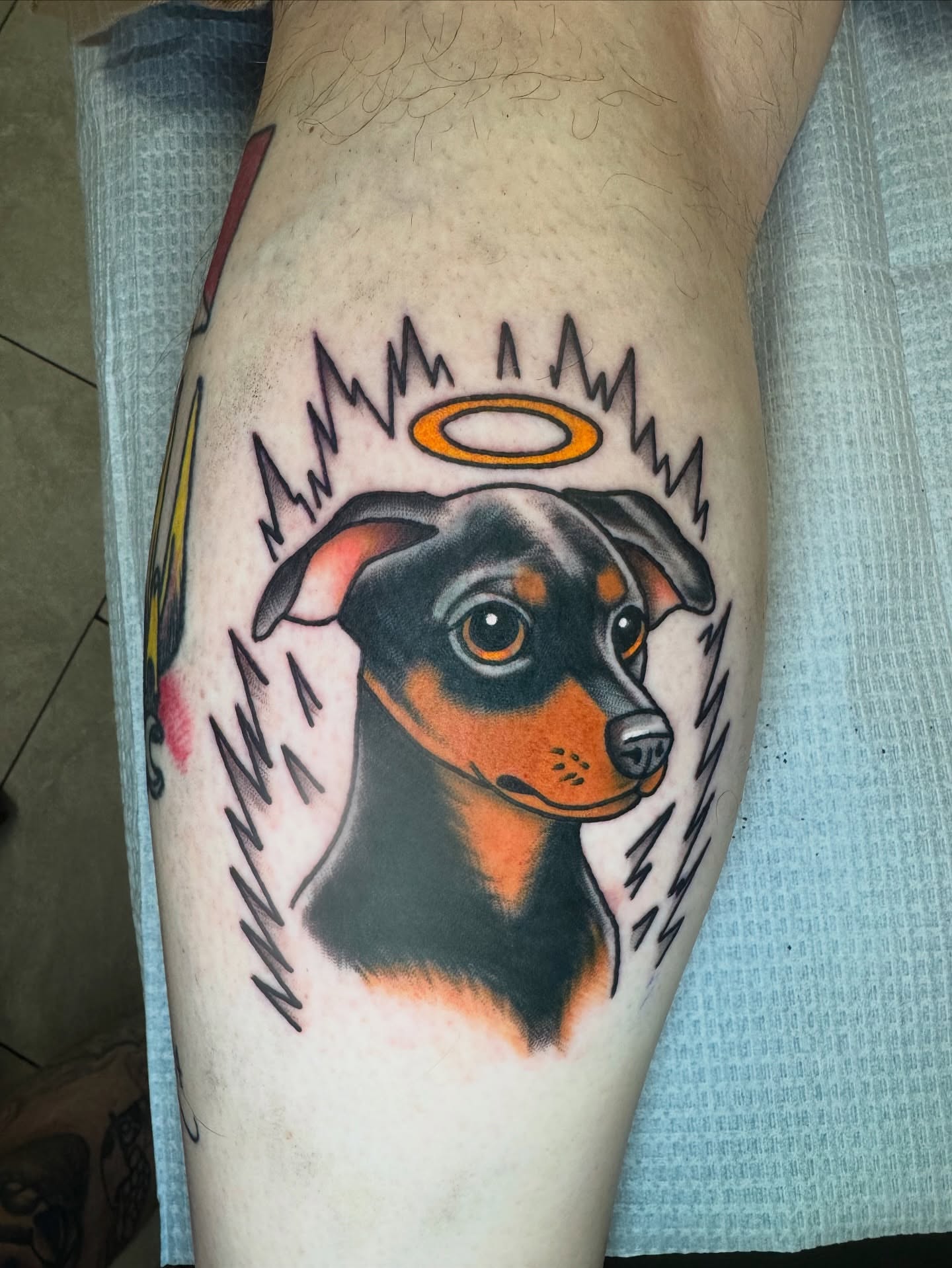 Dog with halo American traditional tattoo on the thigh by Kenneth Gibson
