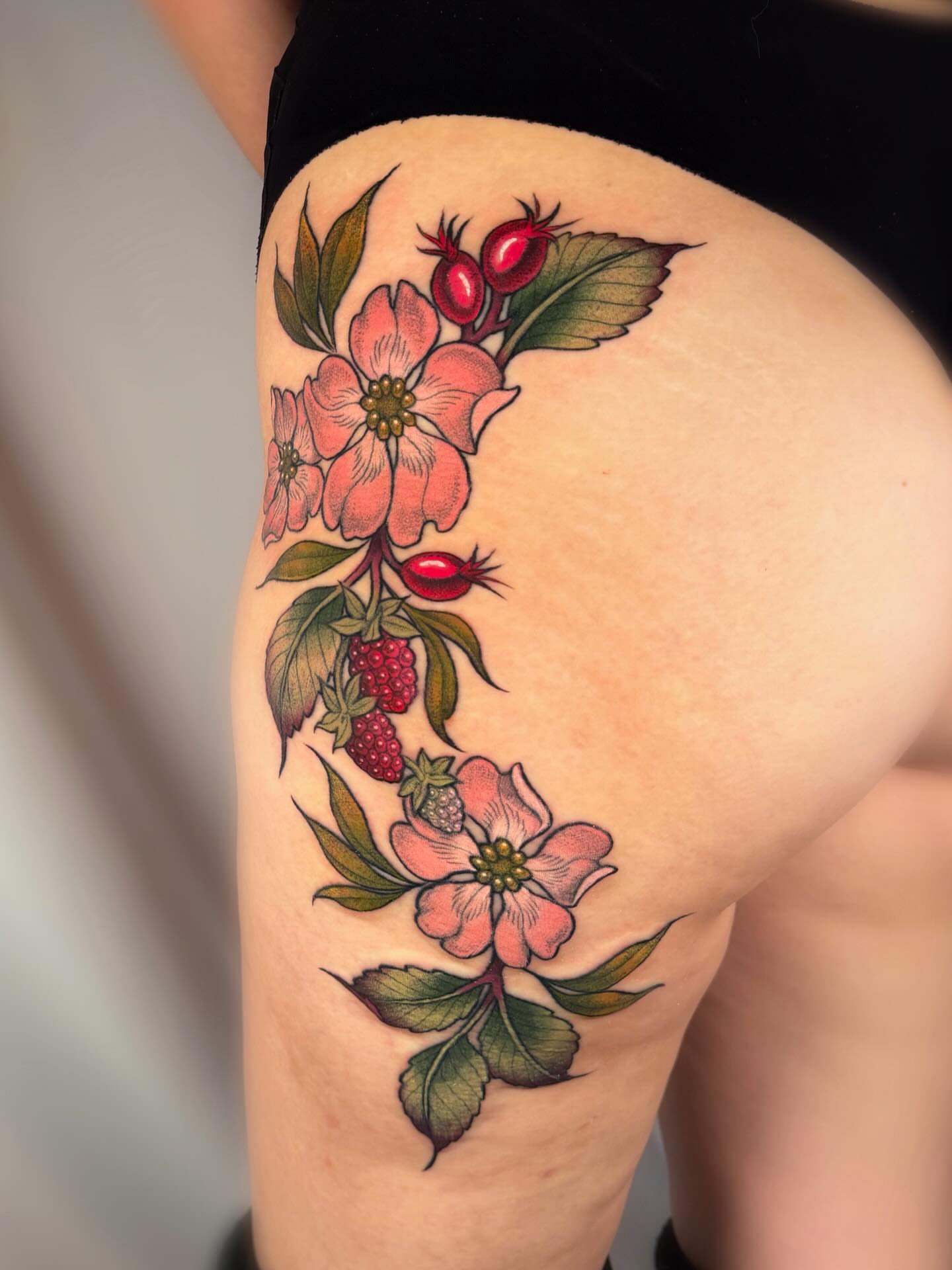Flower and berries American traditional tattoo on the thigh by leanna patterson, Ruston, Louisiana