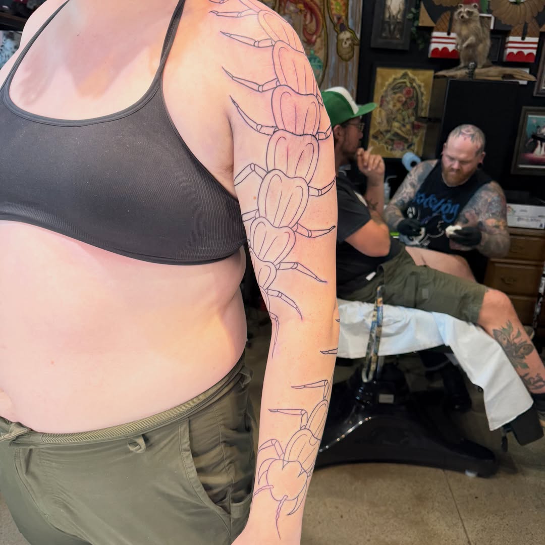 Centipede geometric tattoo on the upper arm by Mercy Dean