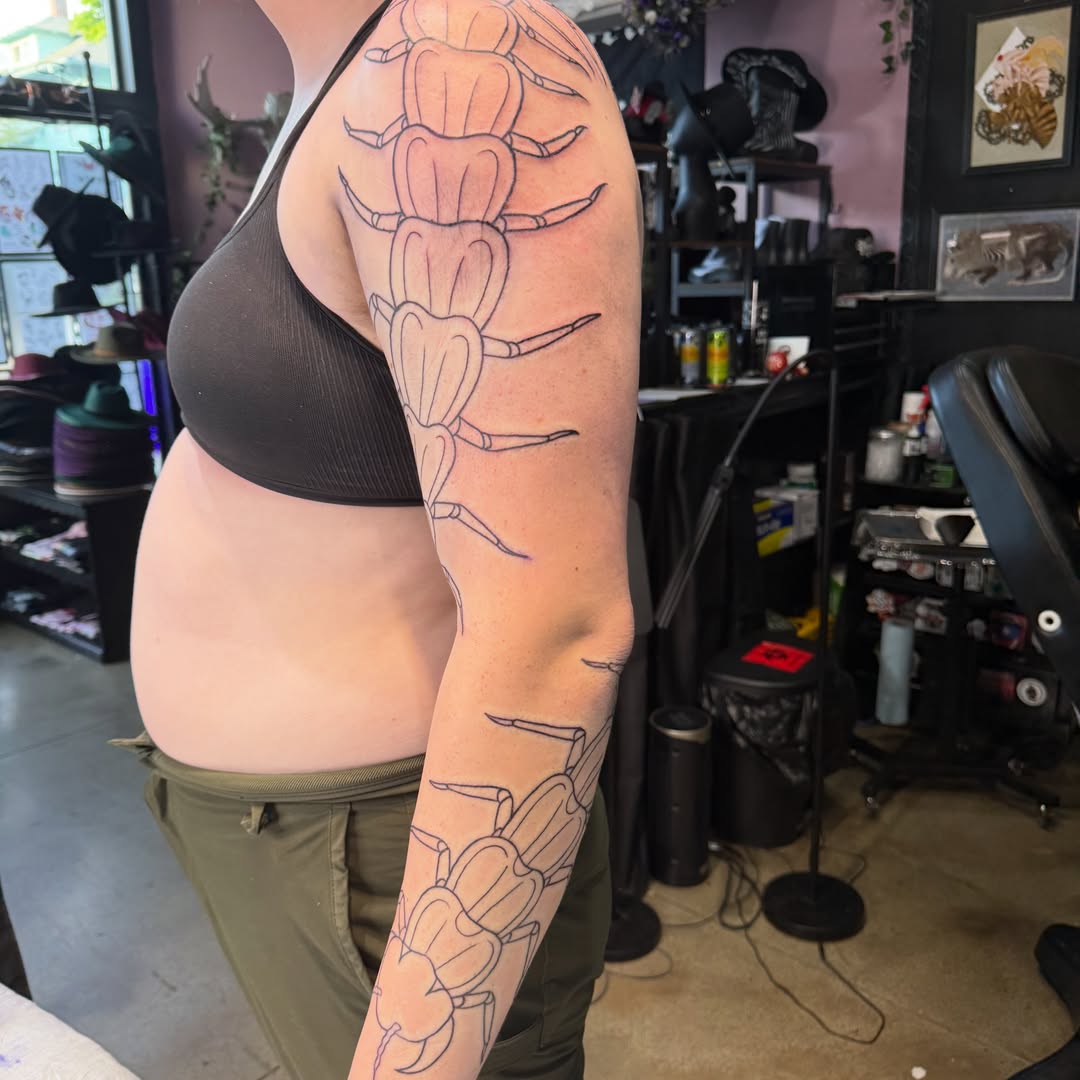Centipede geometric tattoo on the upper arm by Mercy Dean