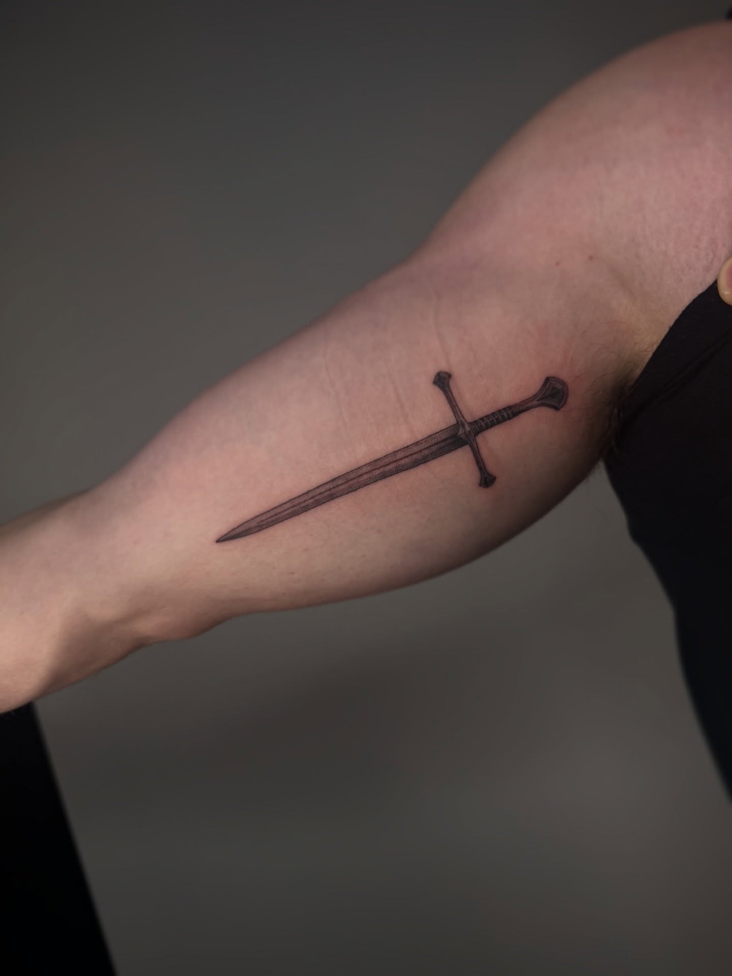 Sword black and grey tattoo on the forearm by Brandon Shelby