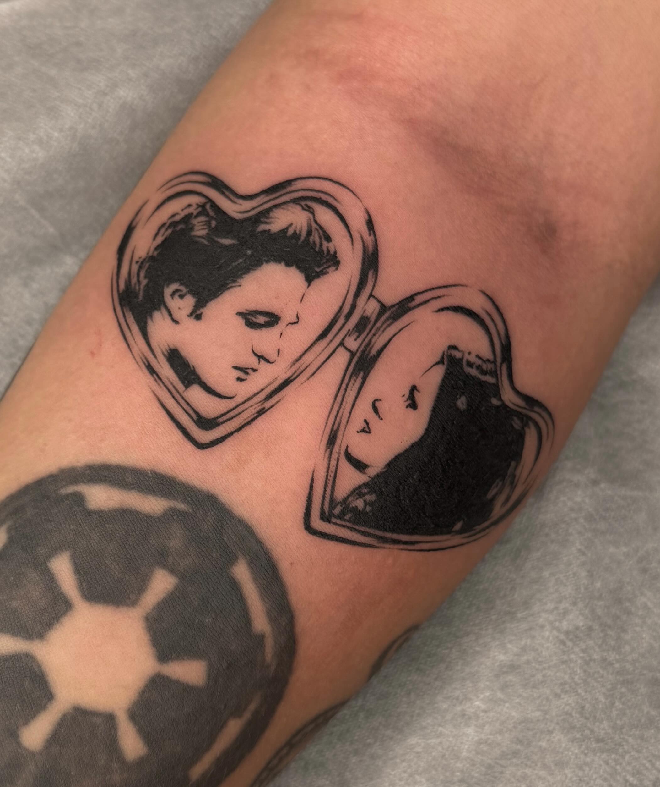 Heart with faces black and grey tattoo on the forearm by Maggie Angulo