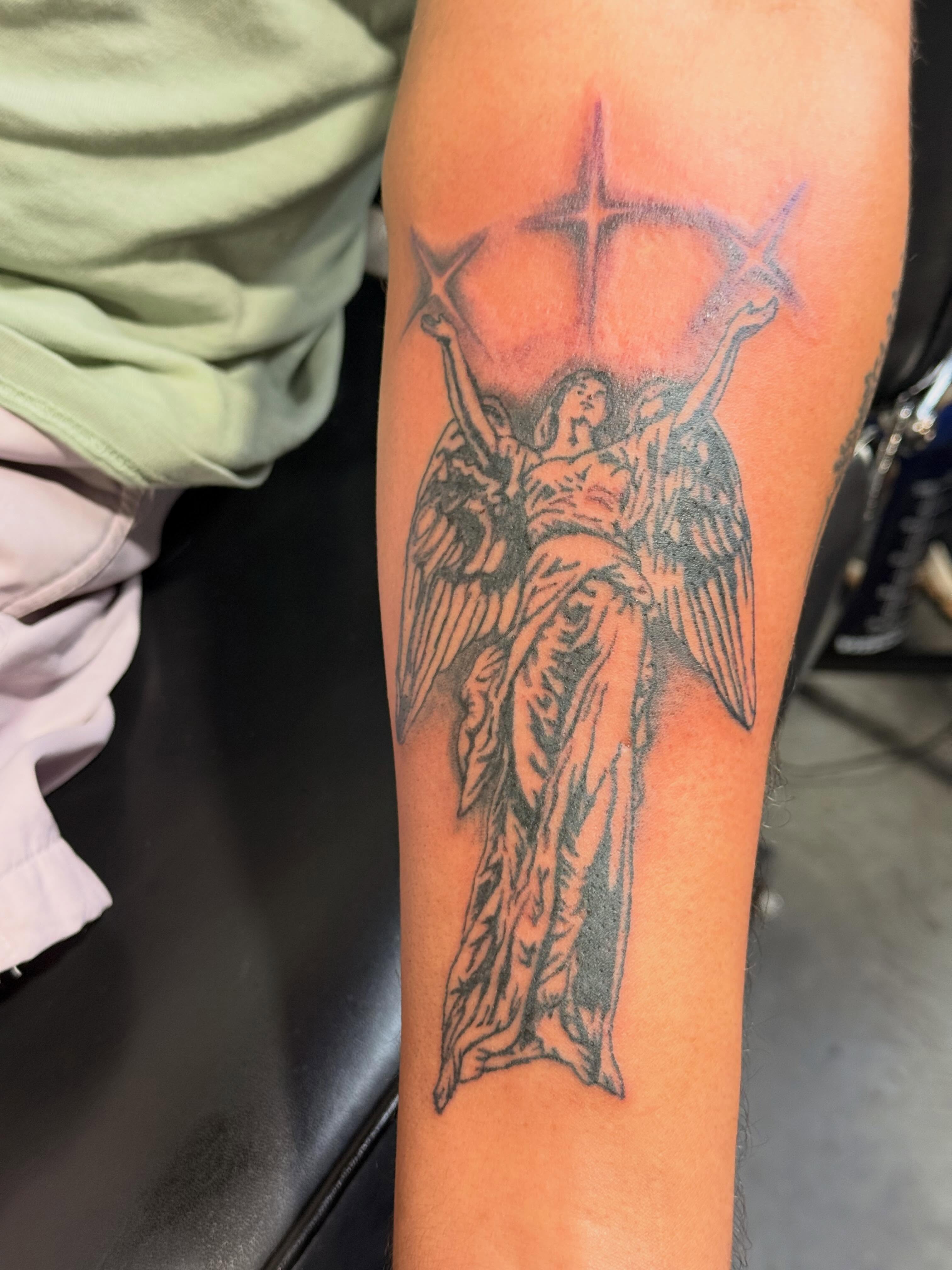 Angel with star black and grey tattoo on the forearm by Jones Eric