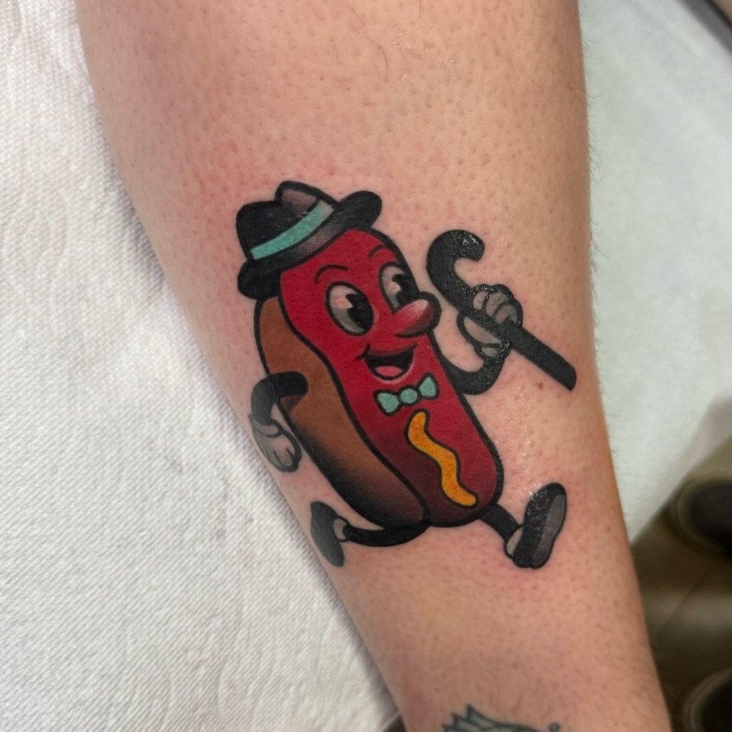 Hot dog character illustrative tattoo on the forearm by Jake lyon
