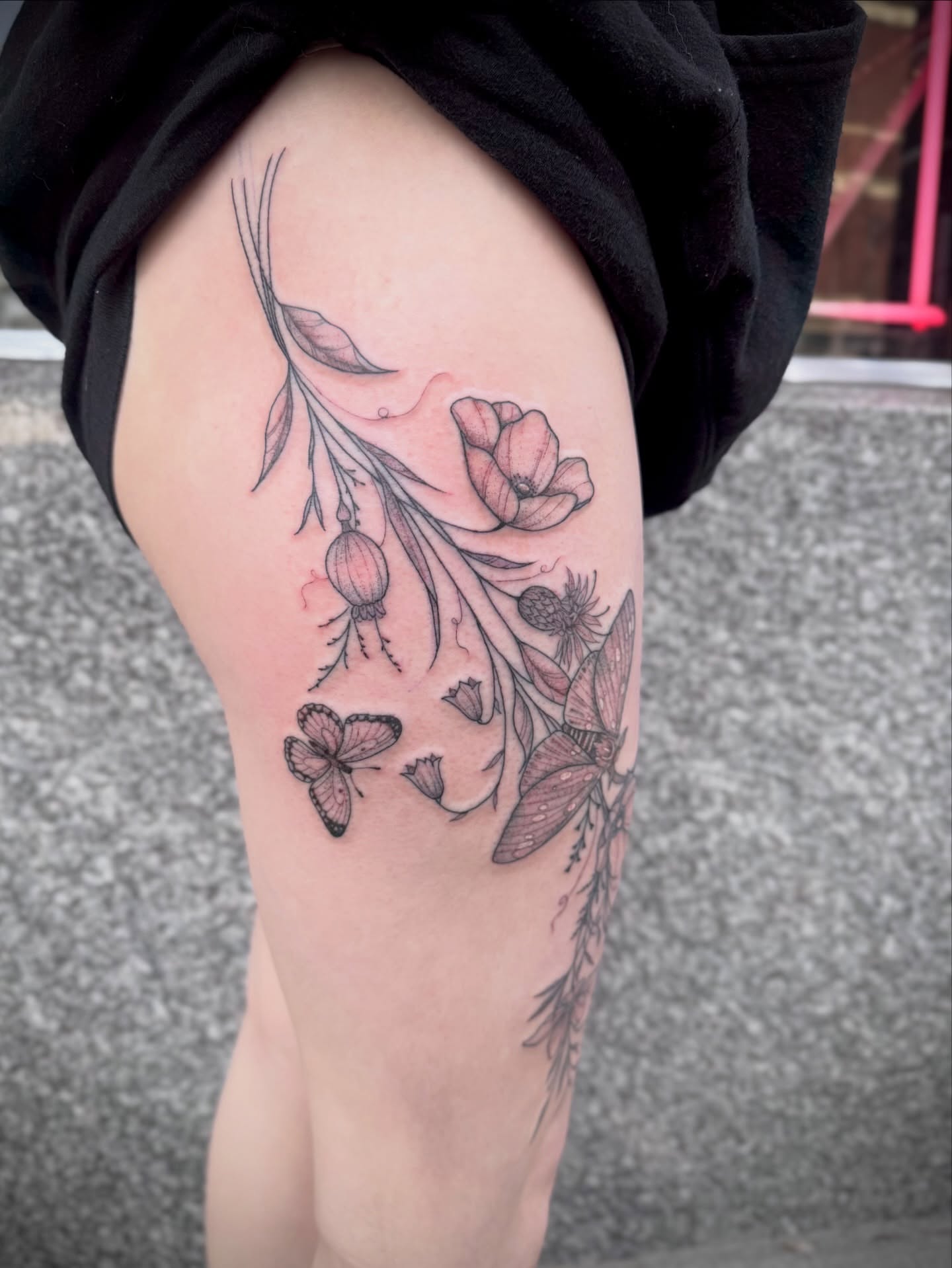 Floral arrangement black and grey tattoo on the thigh by Kylie Allen