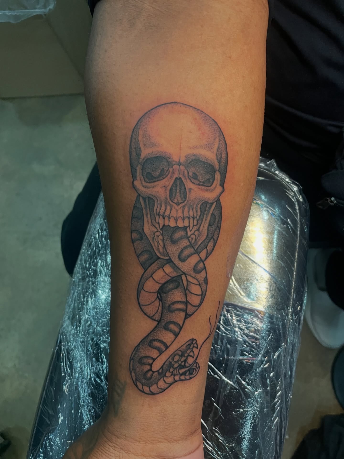 Skull and snake black and grey tattoo on the forearm by Collie Mills, Philadelphia, Pennsylvania