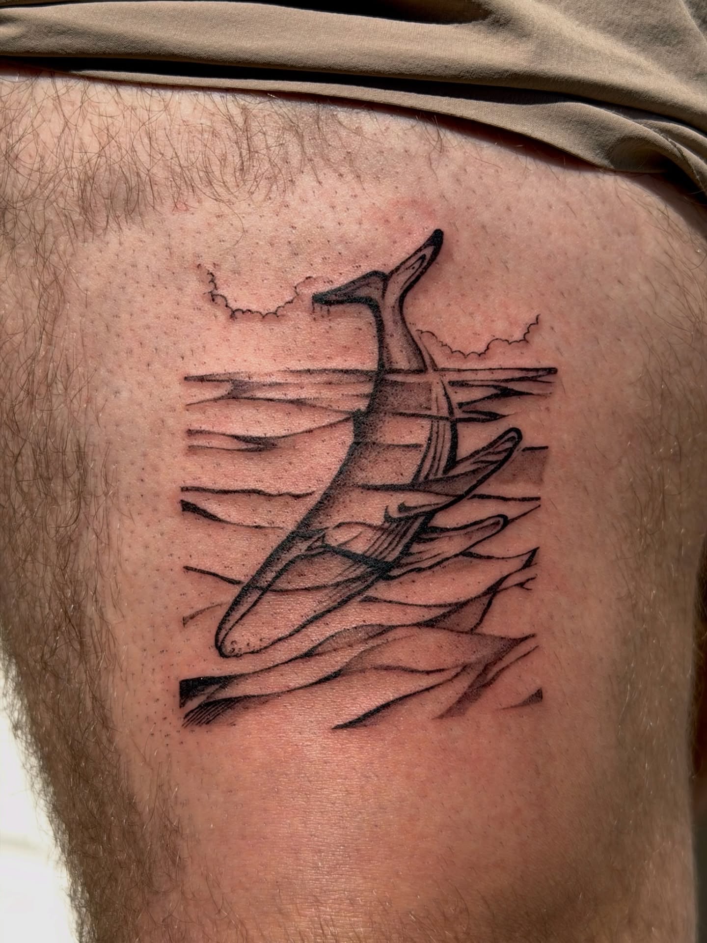 Whale and waves black and grey tattoo on the thigh by Kingtide Ink