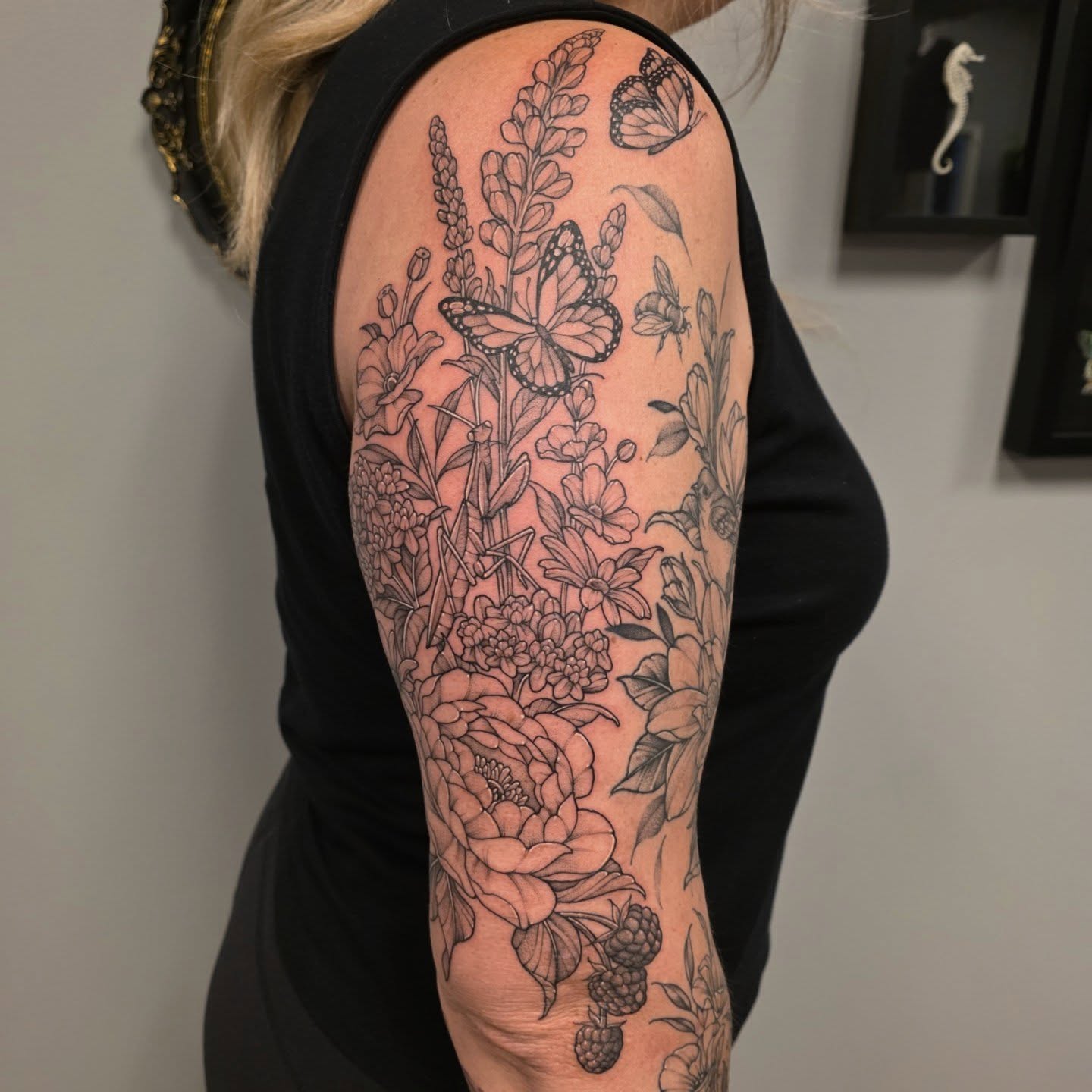 Floral bouquet with butterflies realism tattoo on the upper arm by Dani Bond