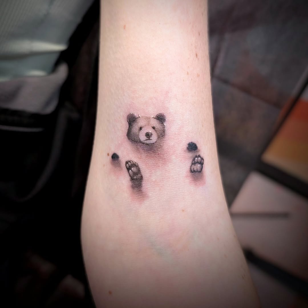 Bear peeking out realism tattoo on the forearm by Rhiannon