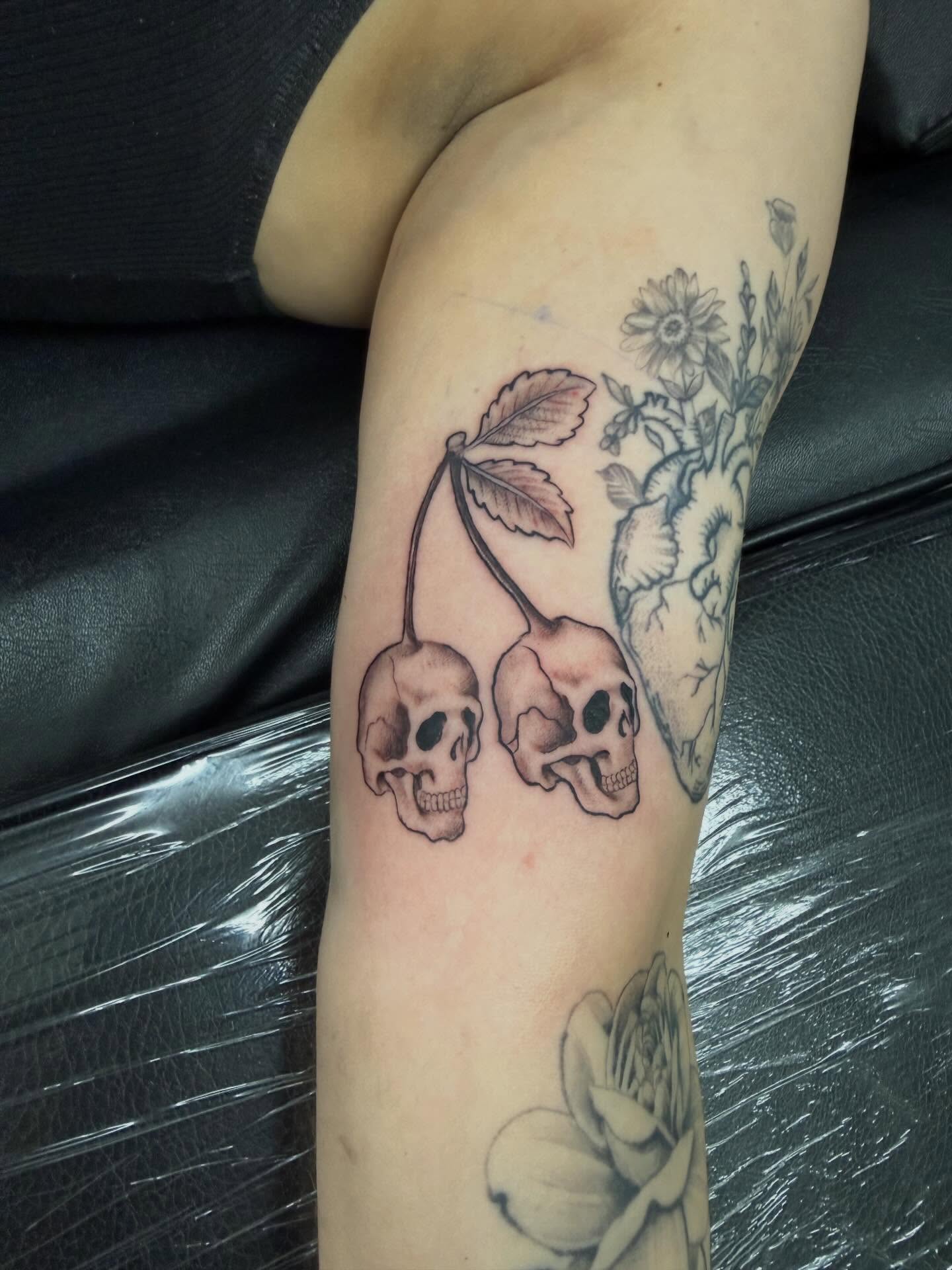 Skulls and flowers black and grey tattoo on the forearm by Daniel Smith