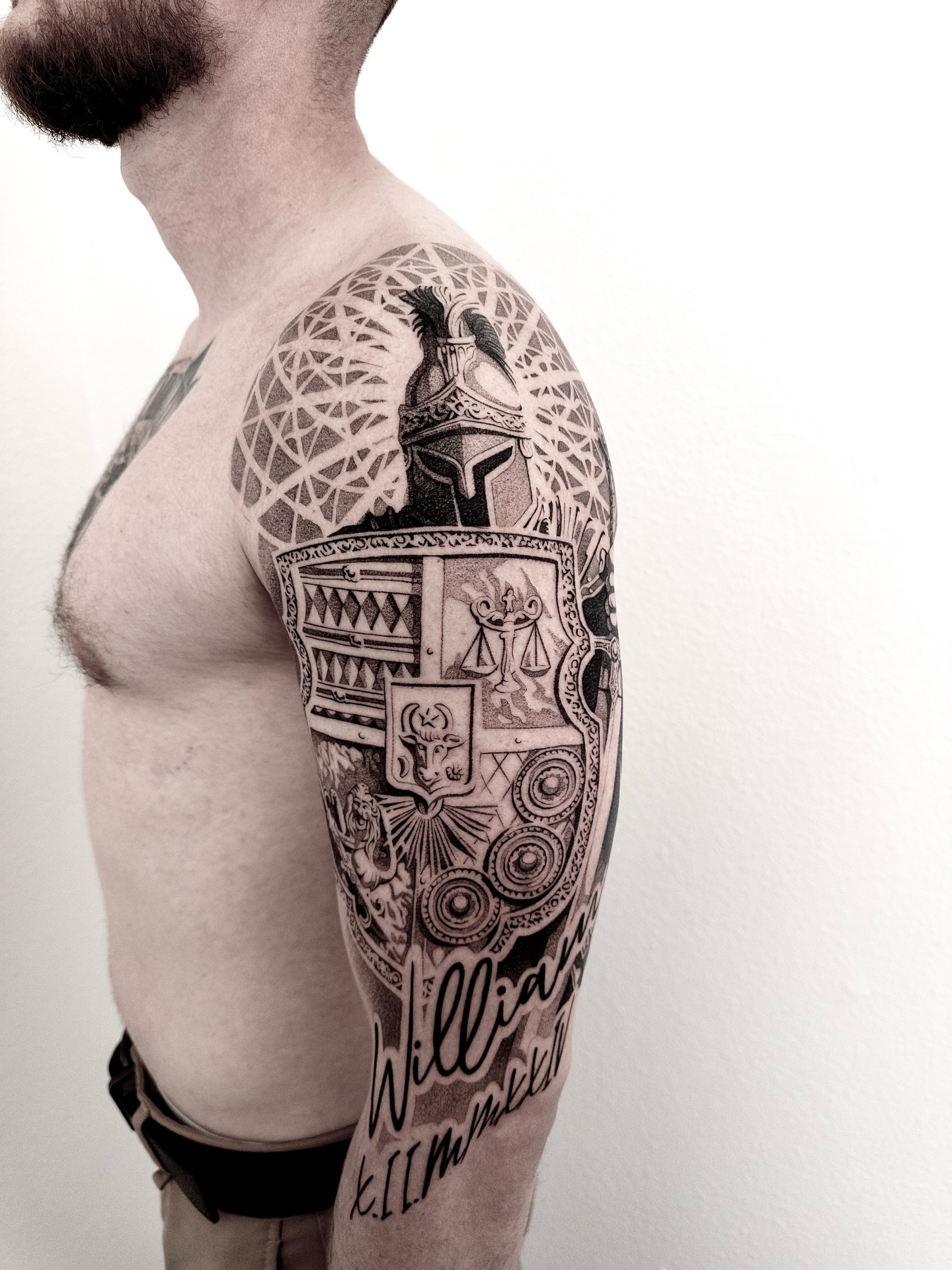 Shield and knight helmet geometric tattoo on the upper arm by sacramento tattoo CA