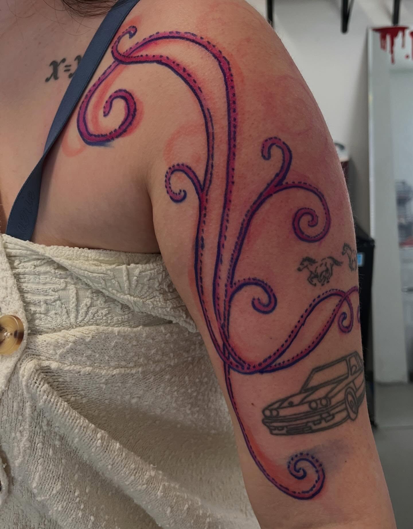Swirls and car new school tattoo on the upper arm by Gabbie