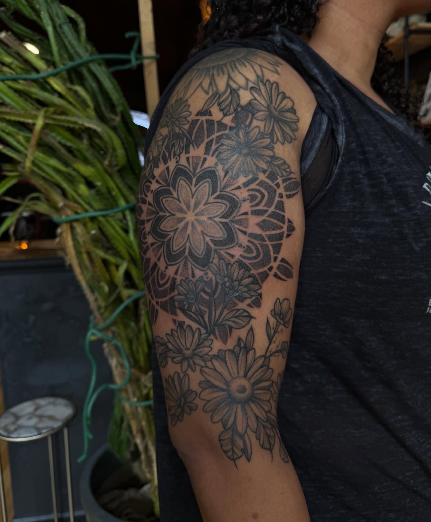 Floral pattern black and grey tattoo on the upper arm by Allison