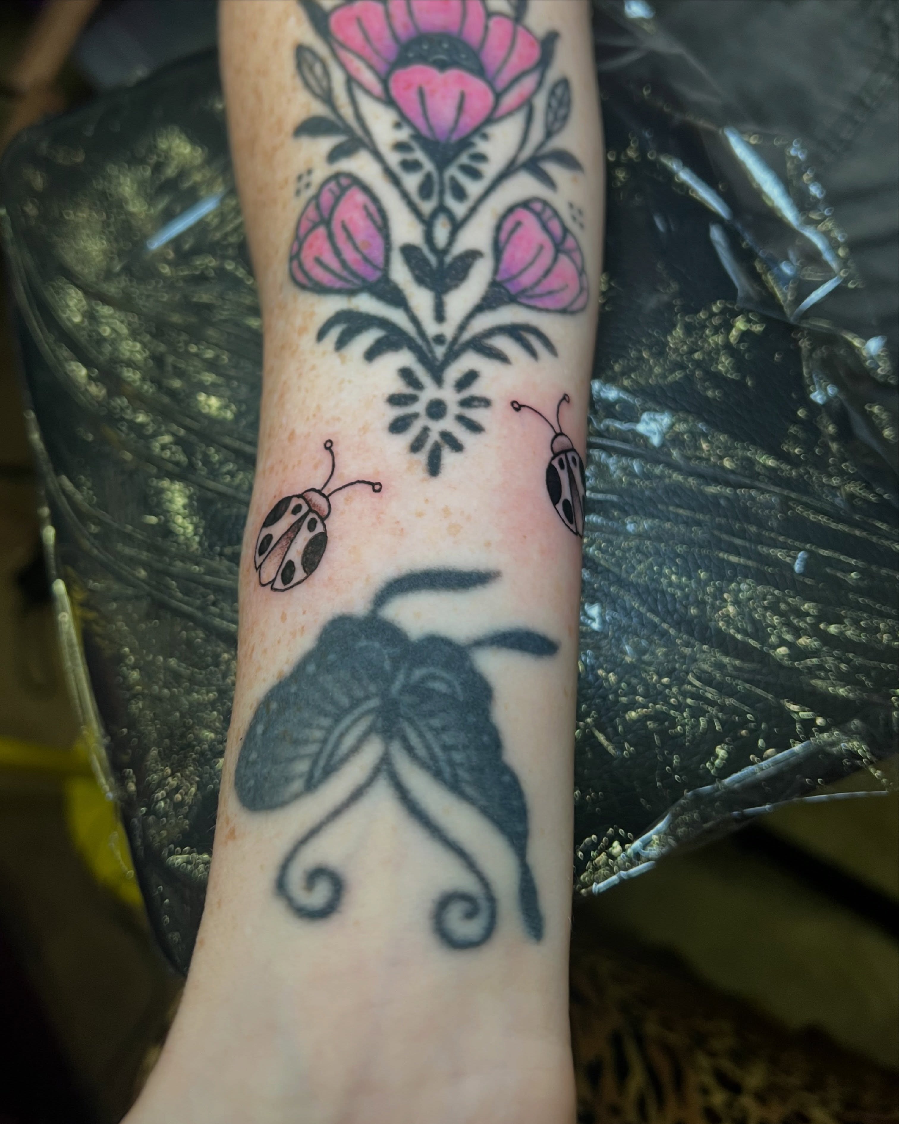 Floral and insects American traditional tattoo on the forearm by Uncomfy Comfort Tattoos LLC