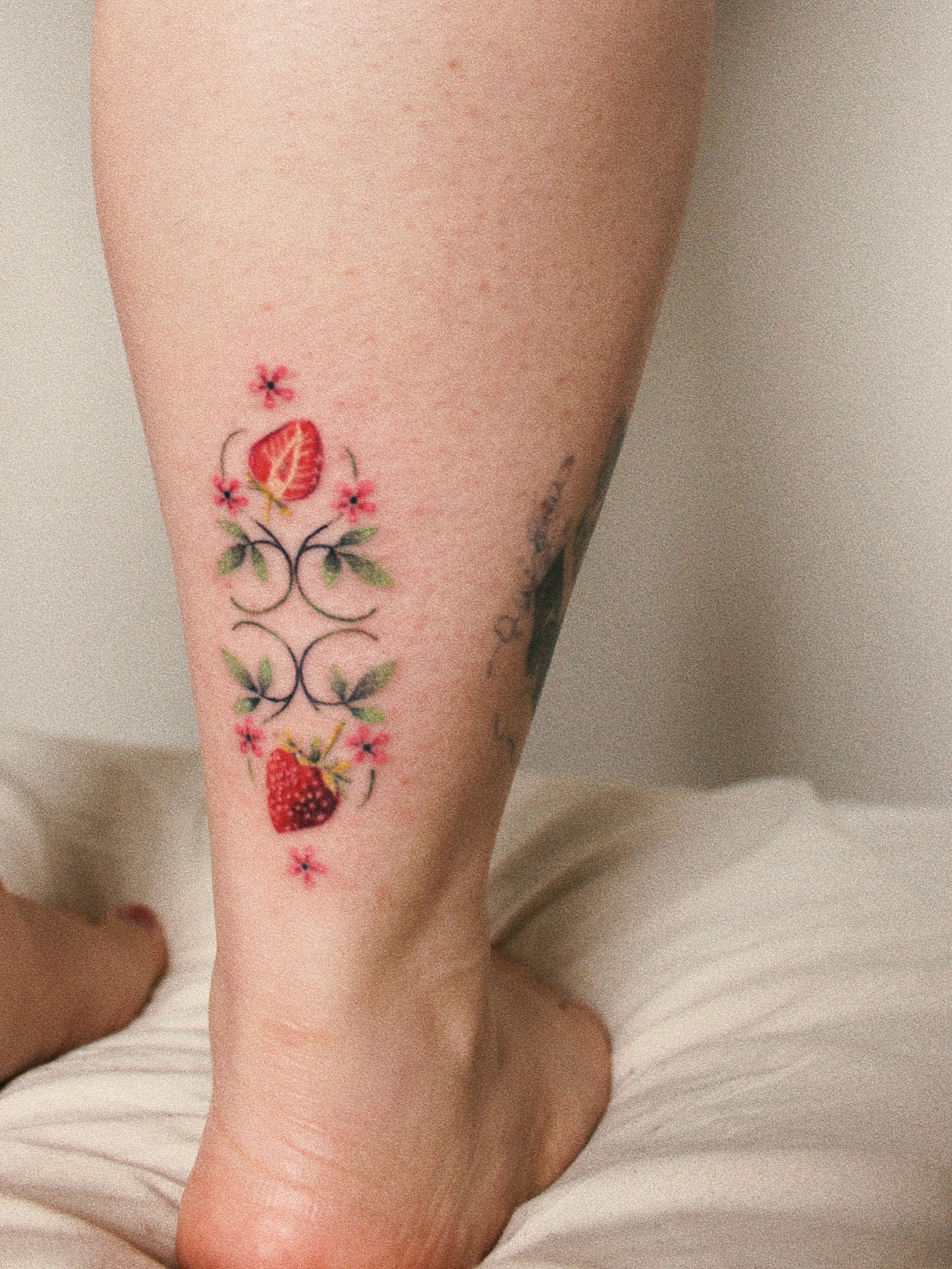 Strawberry and floral vine watercolor tattoo on the calf by Micah Light (color micro realism, Los Angeles, California