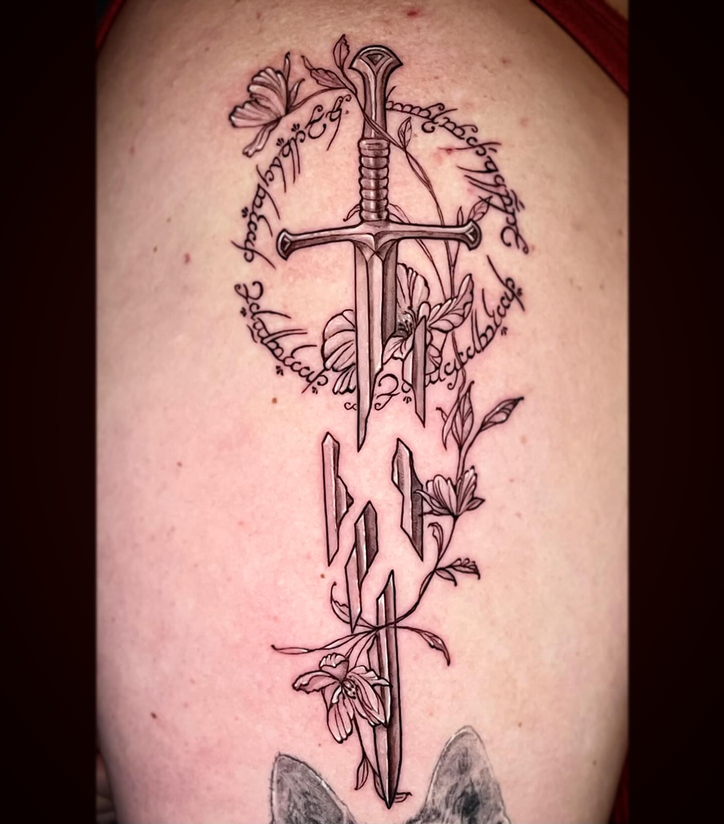 Sword and floral black and grey tattoo on the forearm by Sam DiBiase