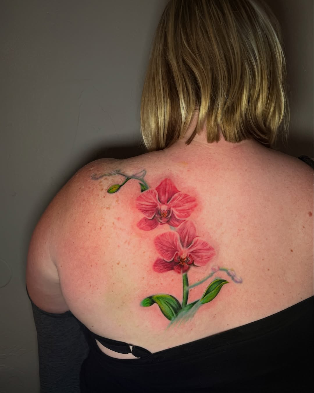 Two pink orchids watercolor tattoo on the back by jayla pantig