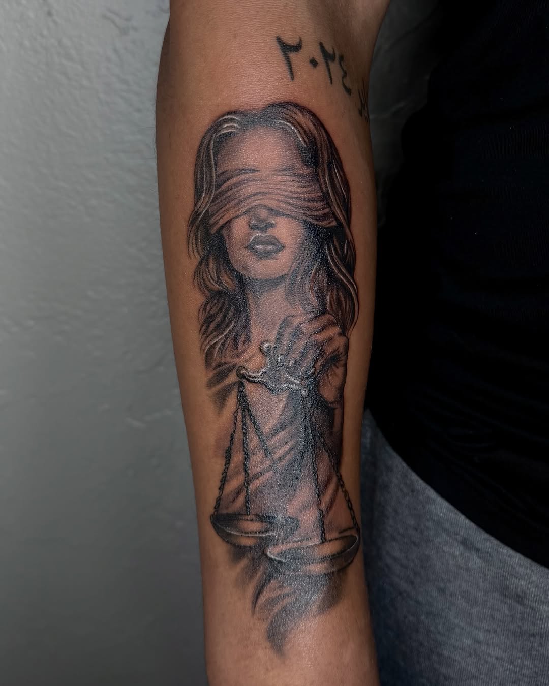 Lady Justice with scales Chicano tattoo on the forearm by jayla pantig