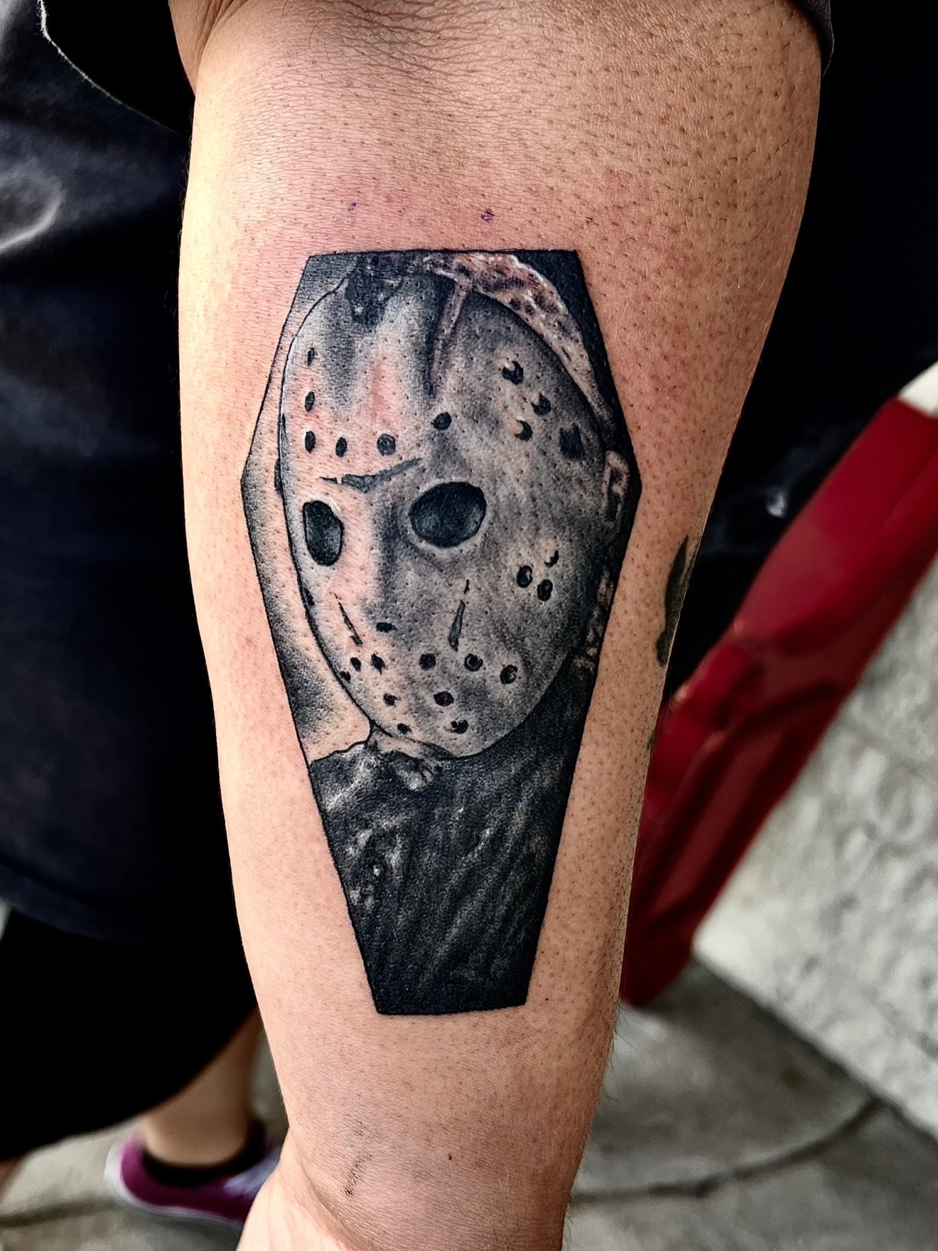 Mask black and grey tattoo on the forearm by Josh Kronauer