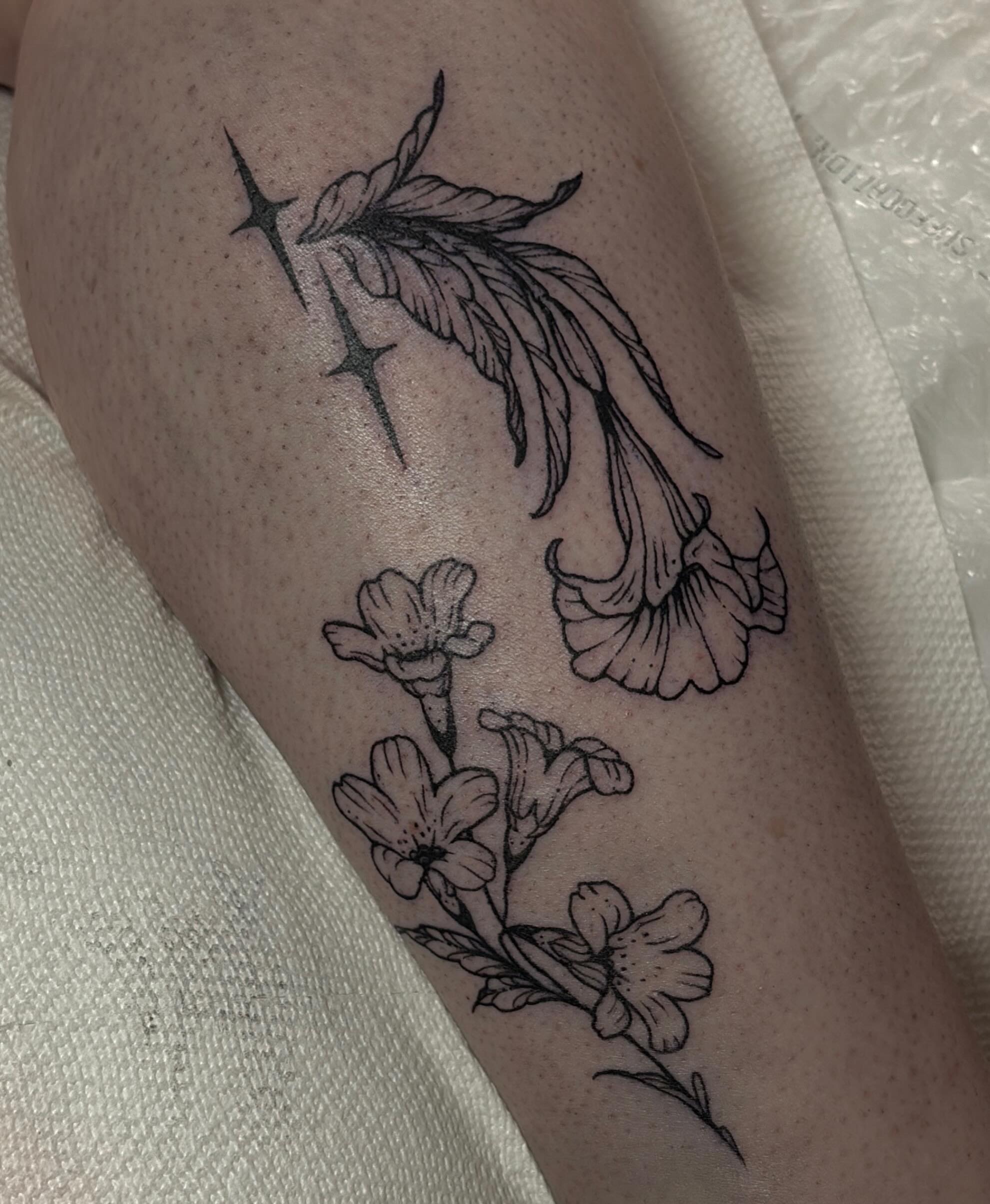 Flowers and feathers black and grey tattoo on the forearm by Harlee Hornsby