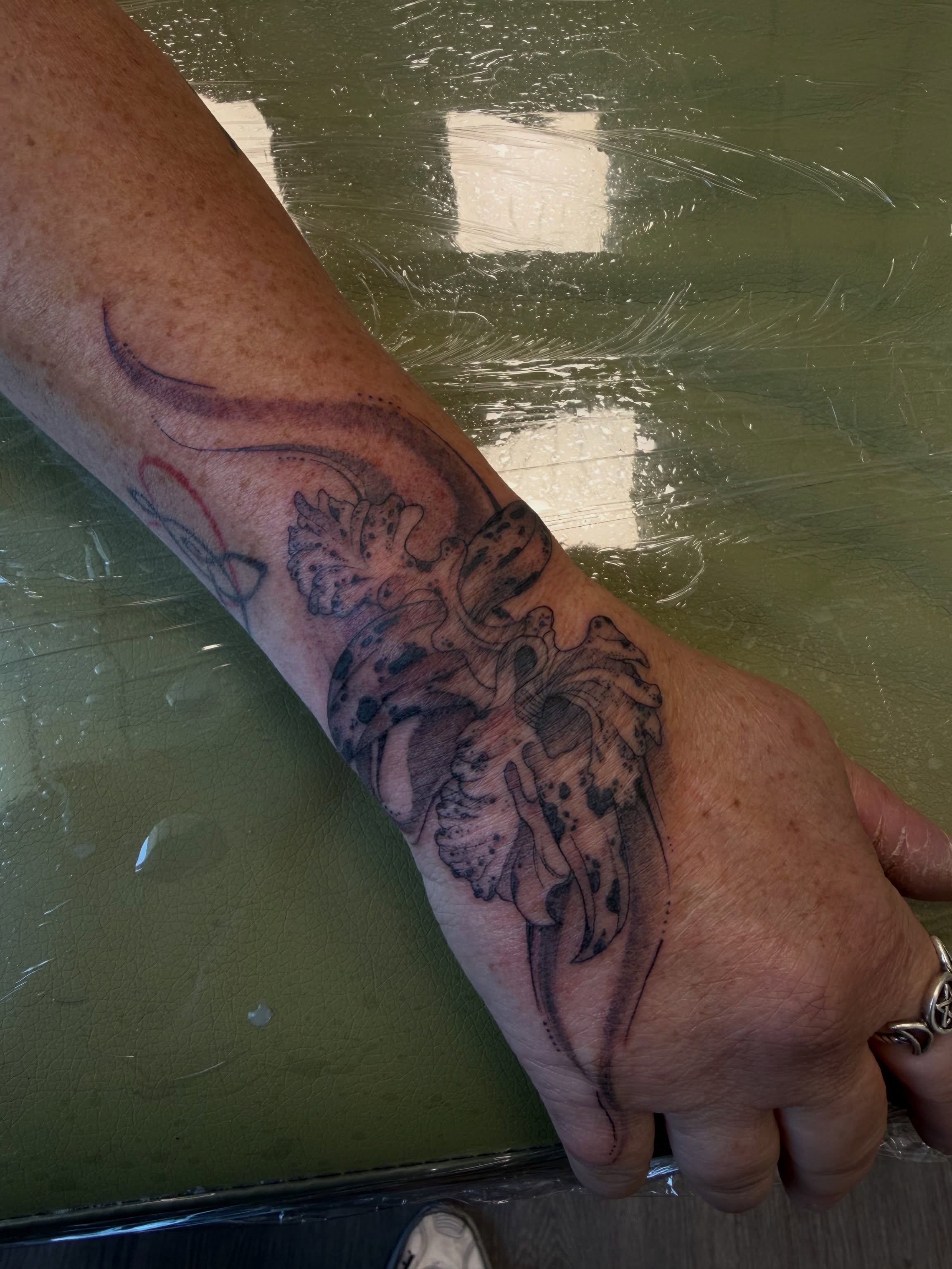 Winged creature black and grey tattoo on the forearm by ashlyn rene