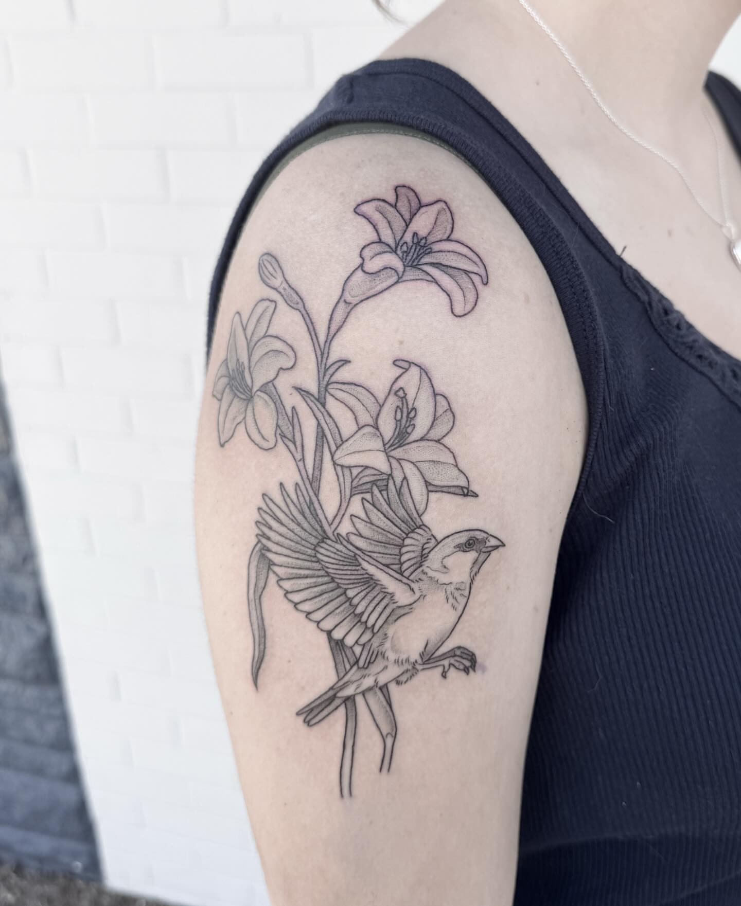 Bird and lilies black and grey tattoo on the upper arm by Audrey Kacel, Holland, Michigan
