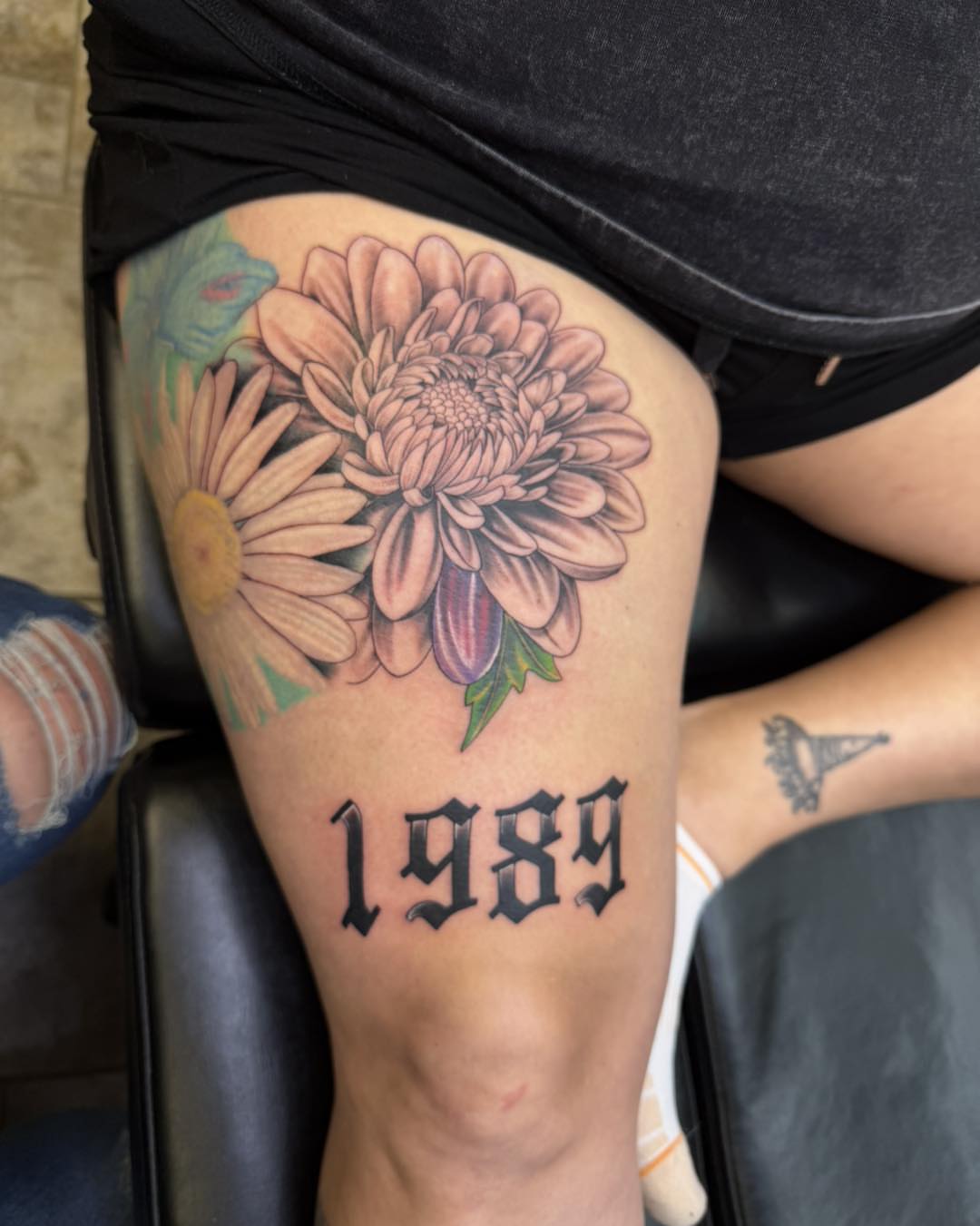 Chrysanthemum and daisy realism tattoo on the thigh by 𝔻𝕖𝕣𝕣𝕚𝕔𝕜 𝔹𝕦𝕪𝕖𝕒, East Aurora, New York
