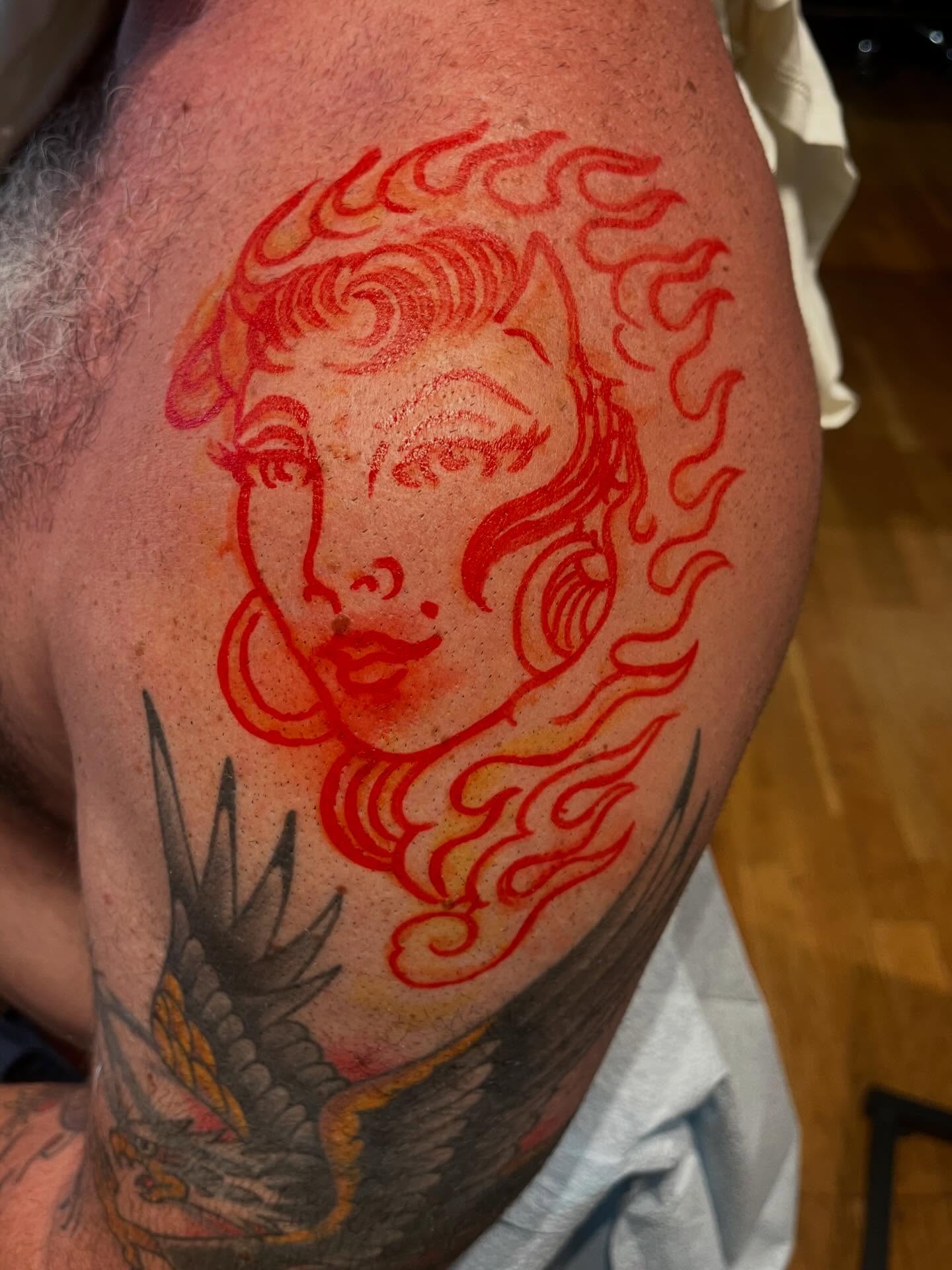 Flame-wrapped woman American traditional tattoo on the upper arm by Graham Niles