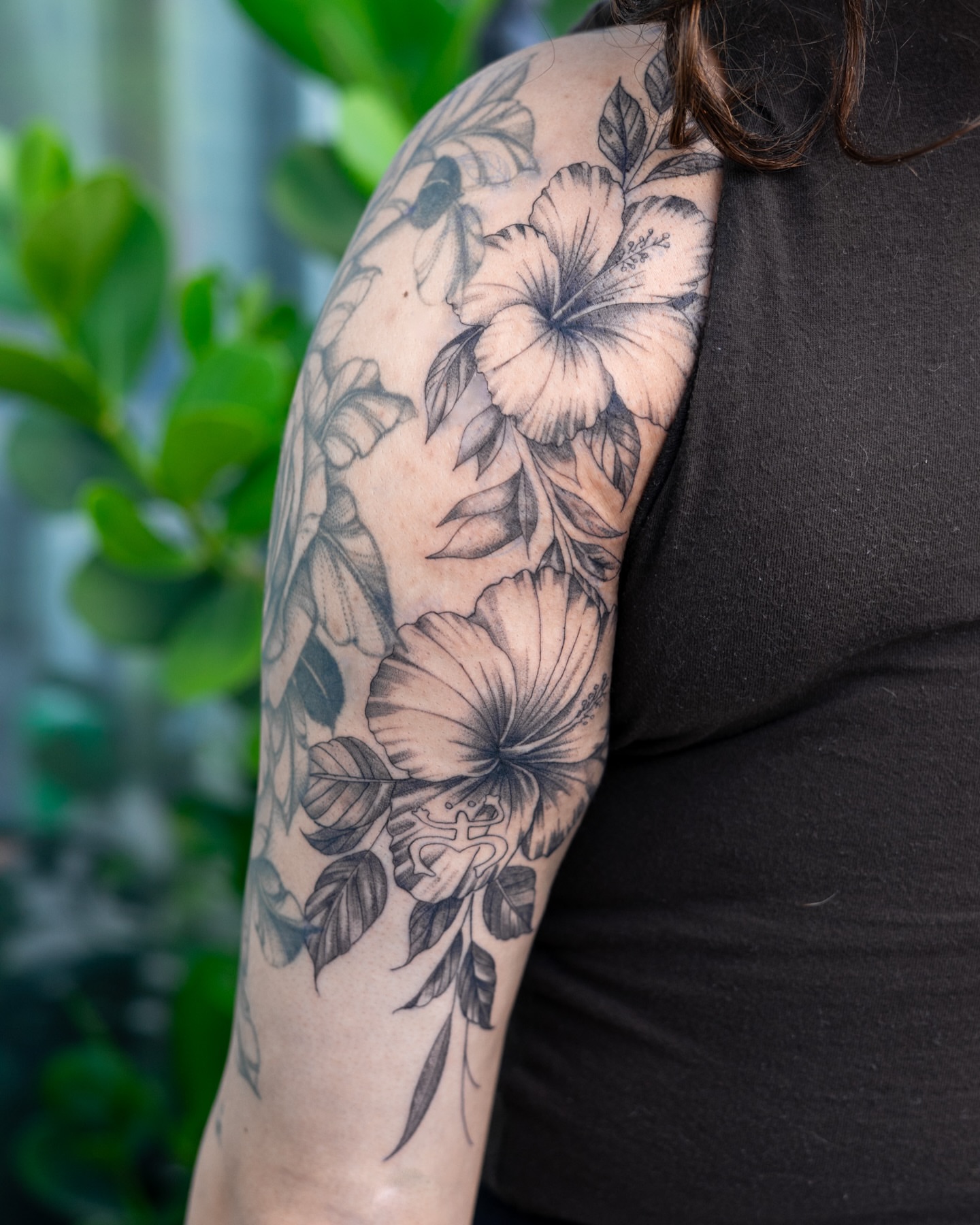Hibiscus flowers black and grey tattoo on the upper arm by The Tattoo Plug