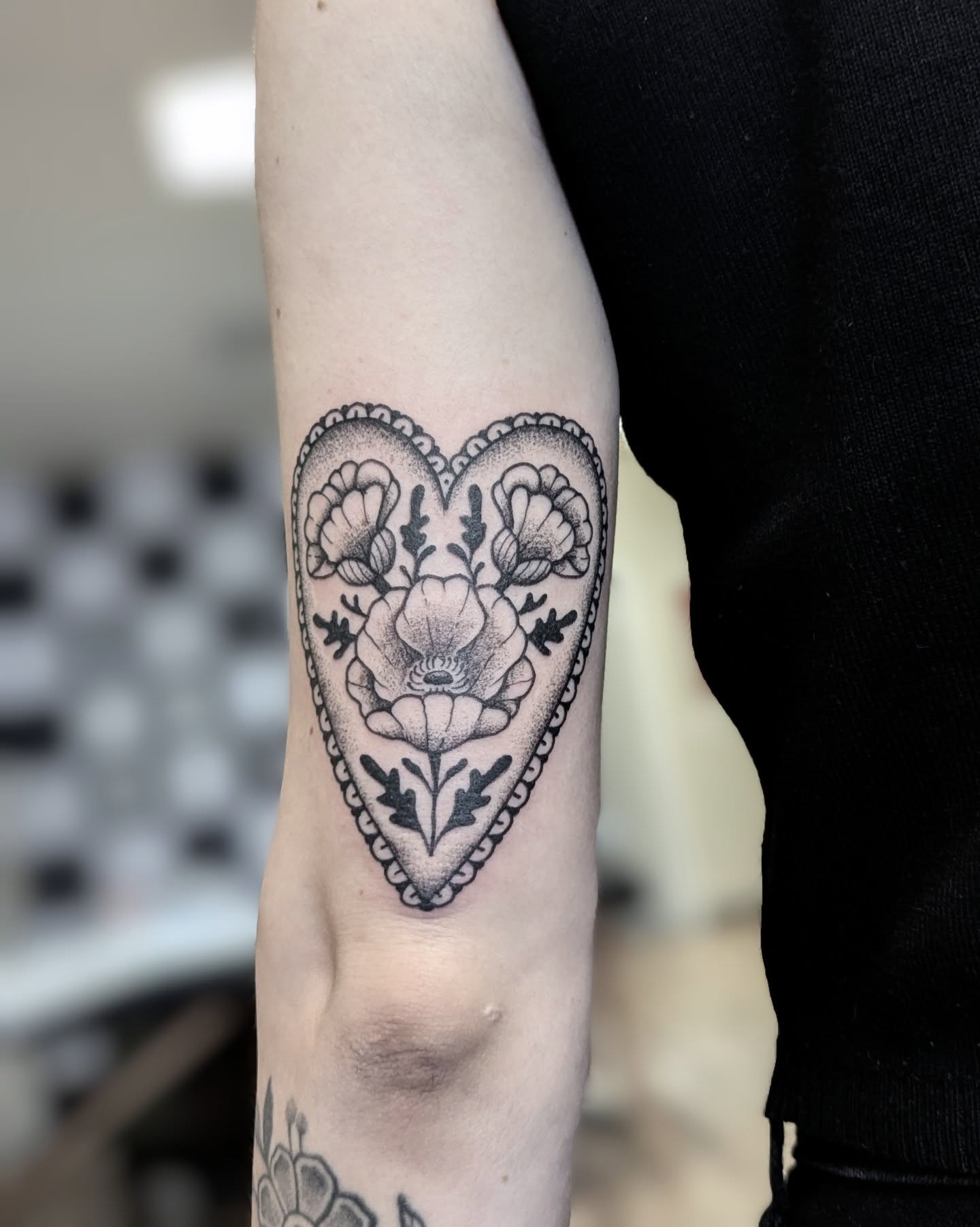 Heart with floral design black and grey tattoo on the forearm by Dani Harkey